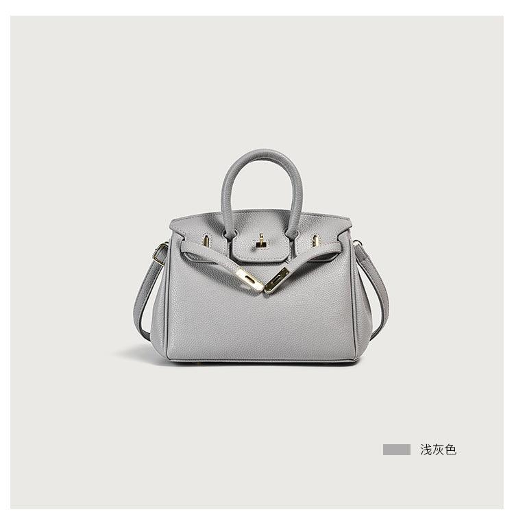 Light gray leather handbag with handles and shoulder strap on display.