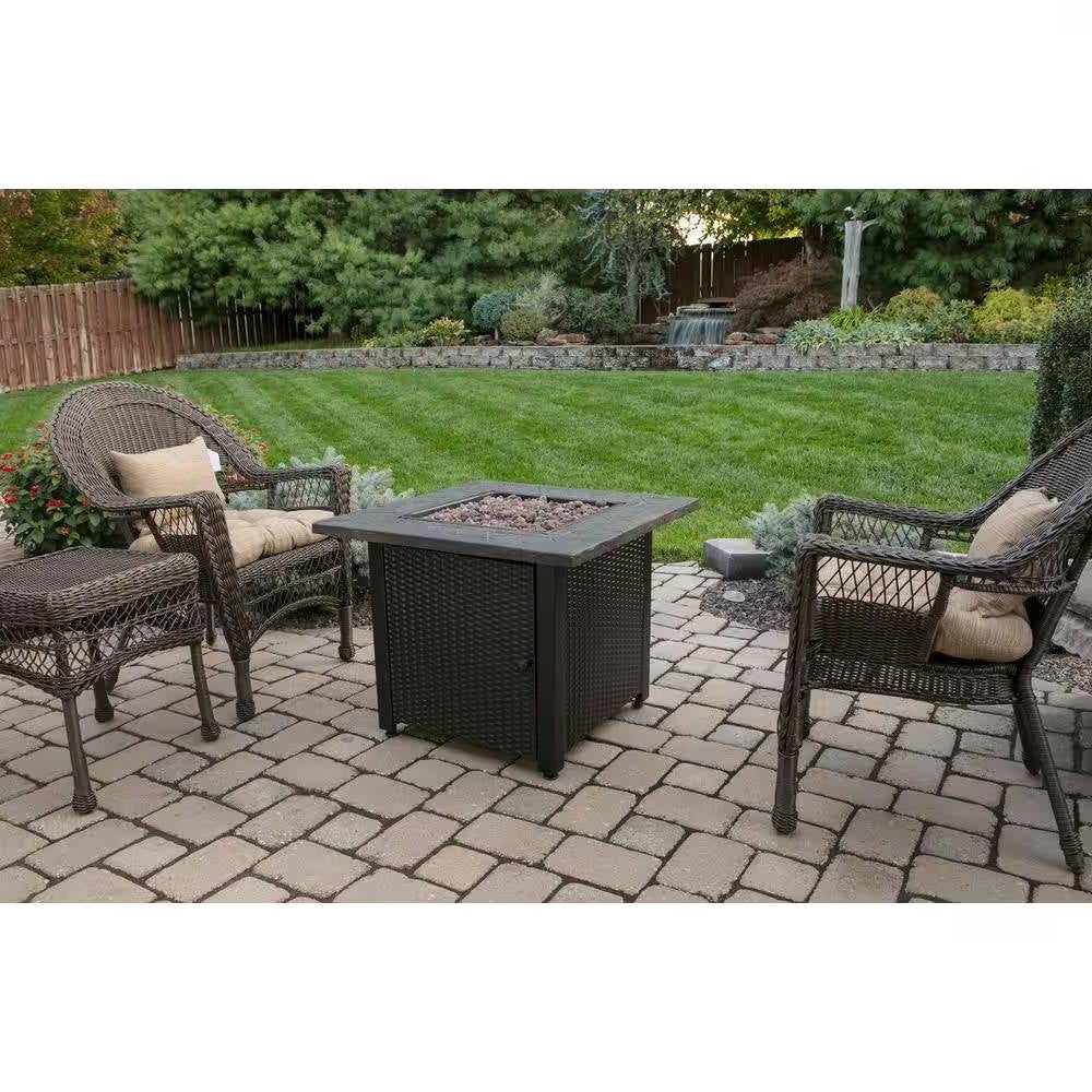 Patio setup with 30-inch Outdoor Bronze LP Propane Gas Fire Pit with Lava Rocks and Cover in garden setting.