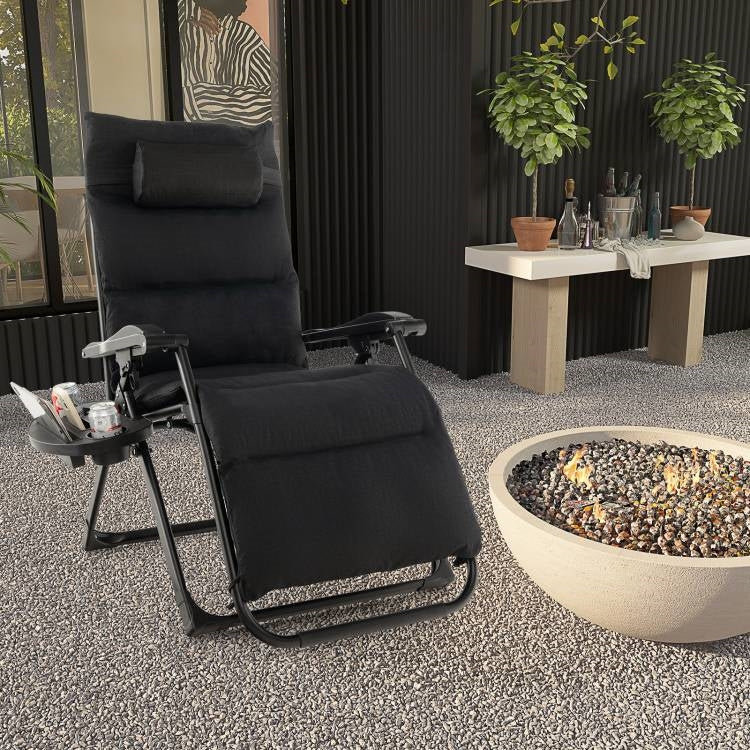 Black Zero Gravity Adjustable Lounge Chair Removable Cushion Cup Holder Tray in outdoor setting with fire pit.