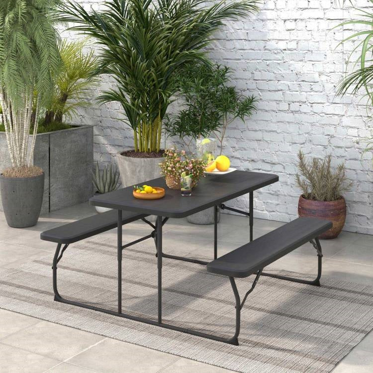 Folding Picnic Table with 2 Benches Outdoor Patio Dining Set in Black on a patio with plants and fruit decoration.