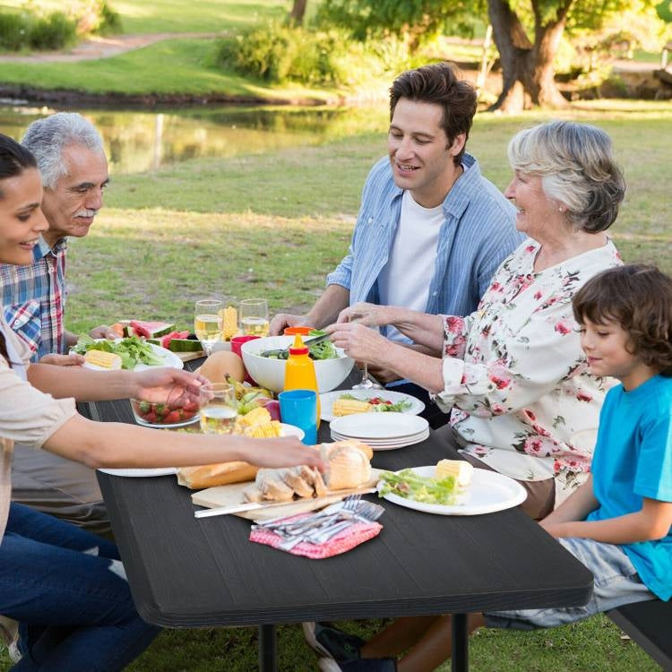 Family enjoying a meal on Folding Picnic Table with 2 Benches Outdoor Patio Dining Set in Black in a park setting.