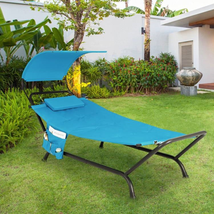 Blue Polyester Chaise Lounge Chair Hammock with Canopy and Storage Bag set up in a garden.