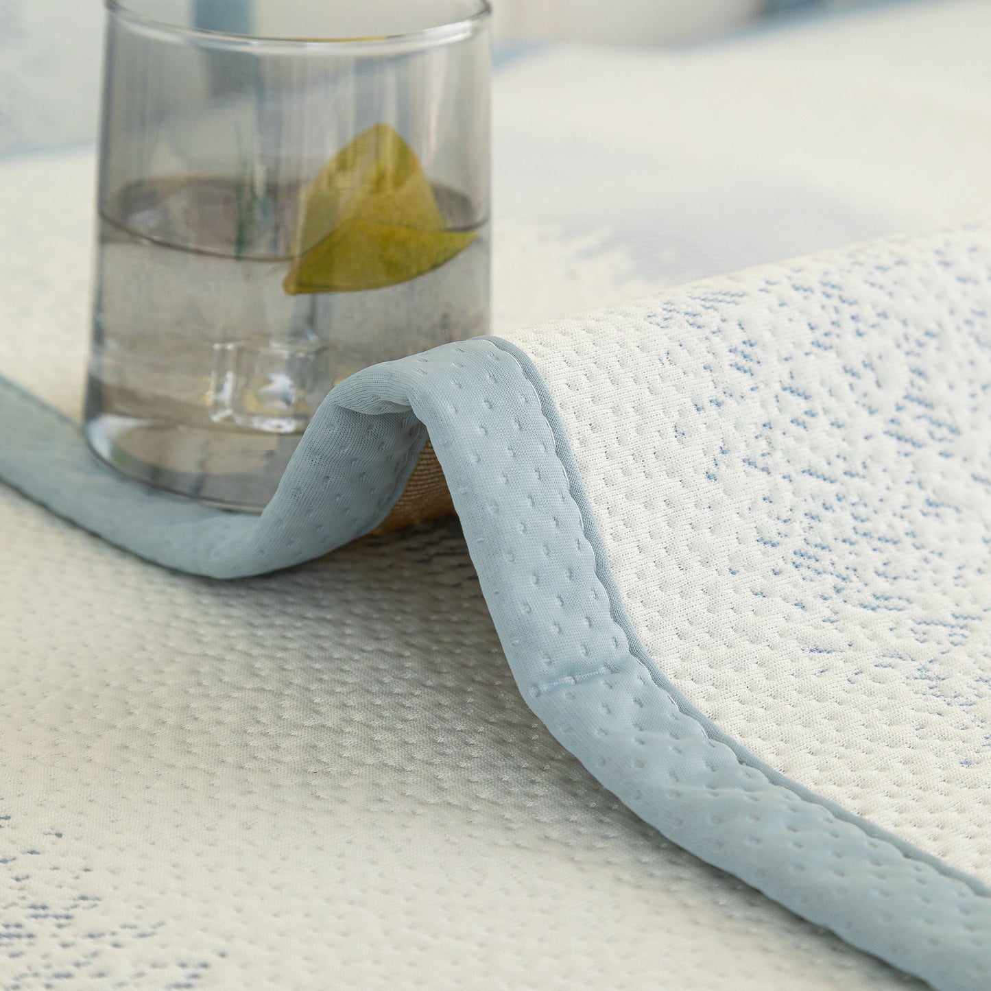 Close-up of the Striped Non-Slip Cooling Couch Cover with a glass on top, featuring breathable fabric and anti-slip backing.