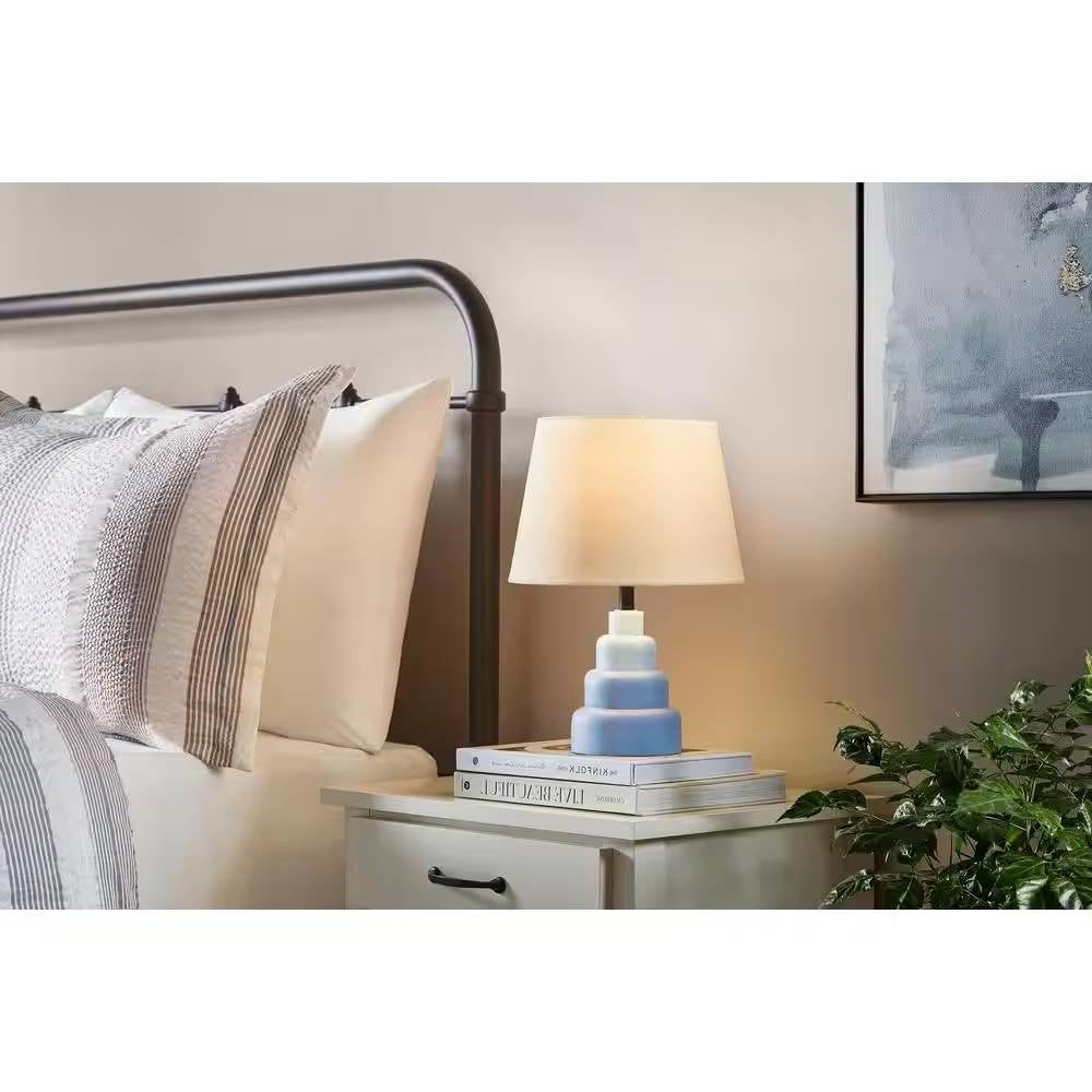 Small Blue Desk Light Table Lamp with White Fabric Shade on bedside nightstand in bedroom setting