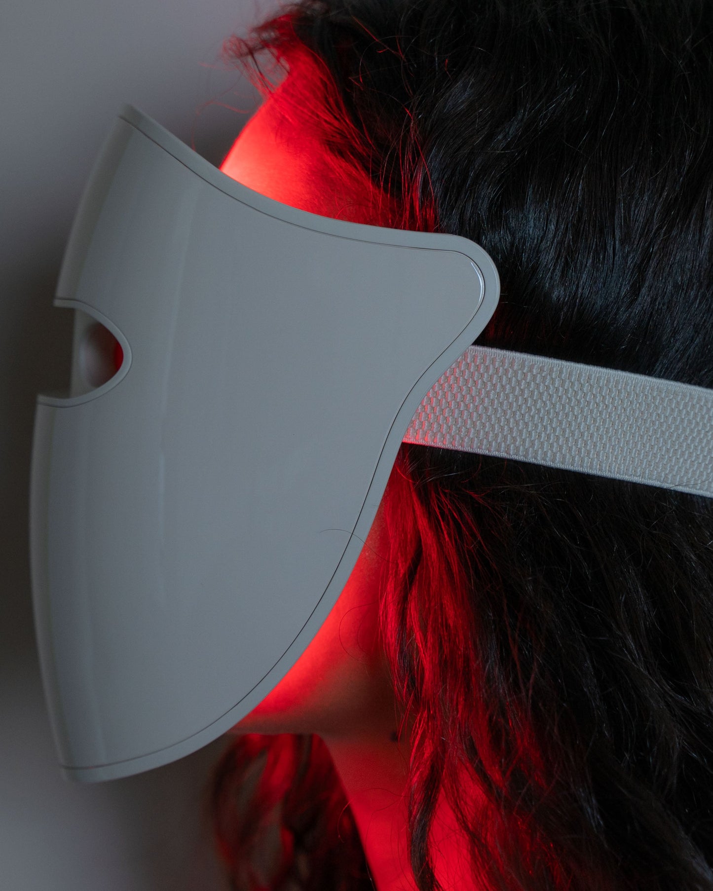 Helio Professional-Grade LED Photon Therapy Mask by Blyss in use, showcasing glowing red LED light on user's face for skincare.