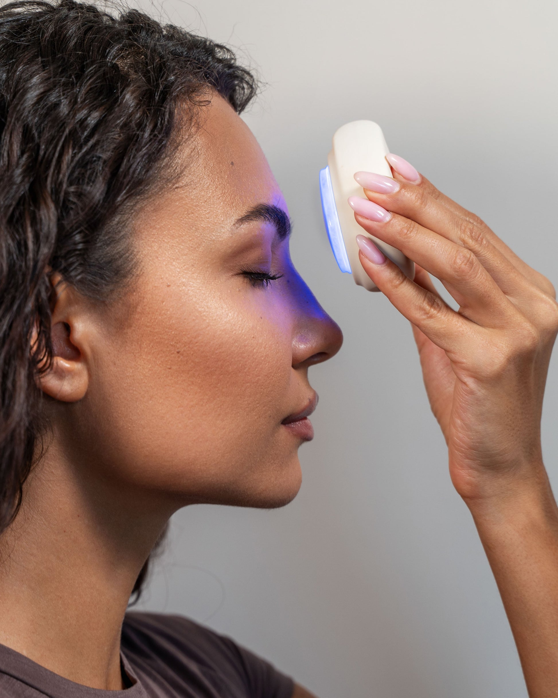 Woman using Photon LED facial rejuvenation device for skin therapy