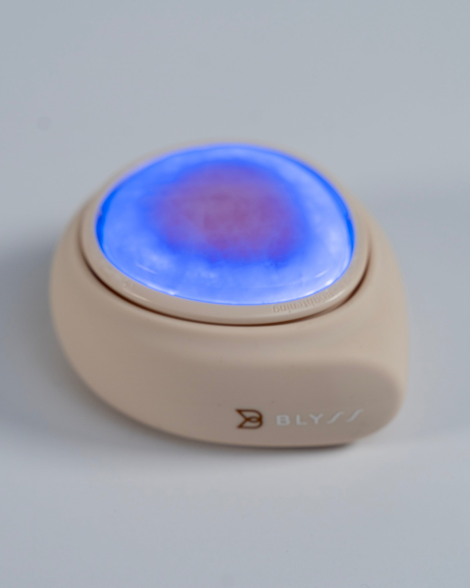 Photon LED facial rejuvenation device featuring blue and red light, compact and palm-sized for easy home skincare therapy.