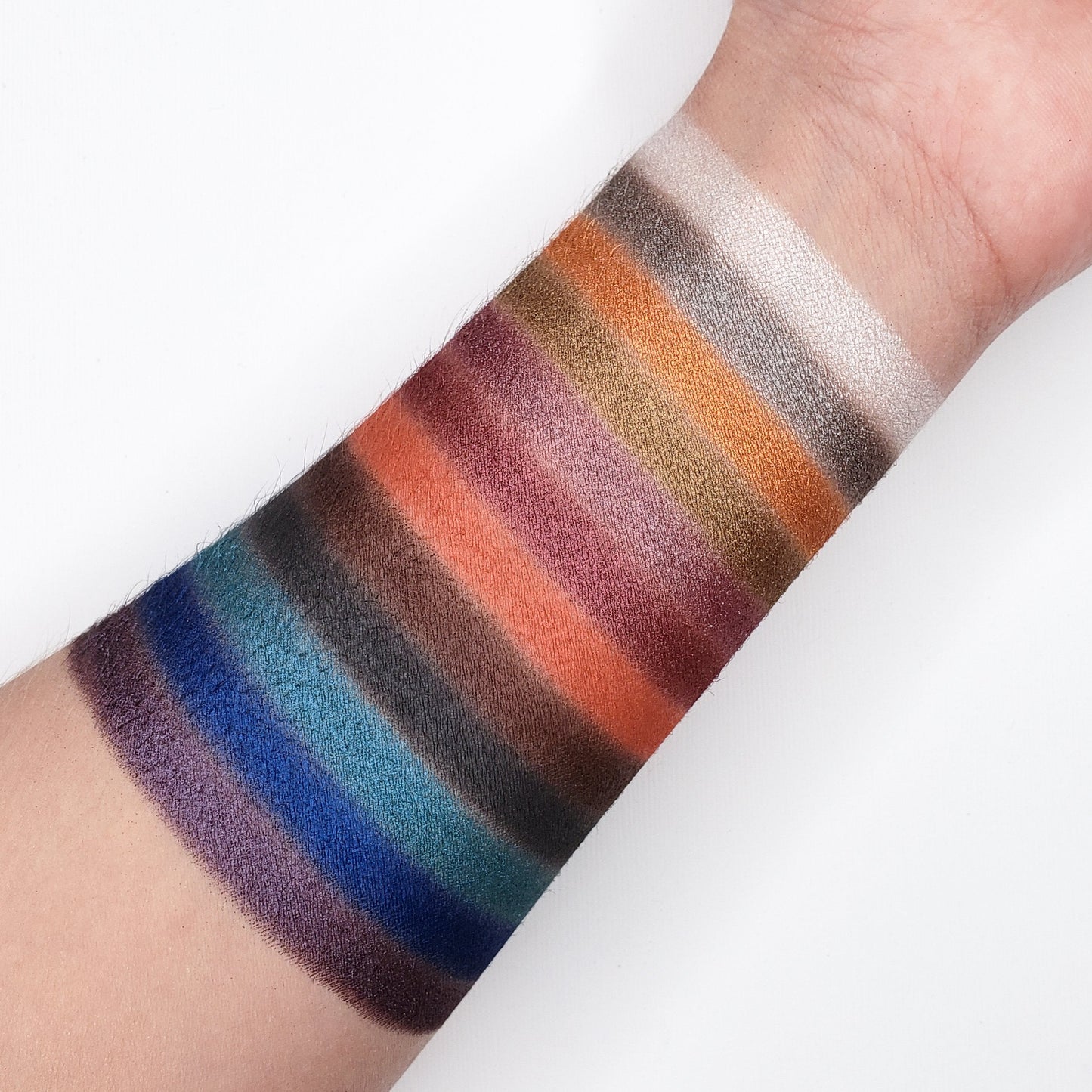Arm showcasing vibrant colors from BOLD EYESHADOW PALETTE CP08 with shimmer, foil, and matte finishes.