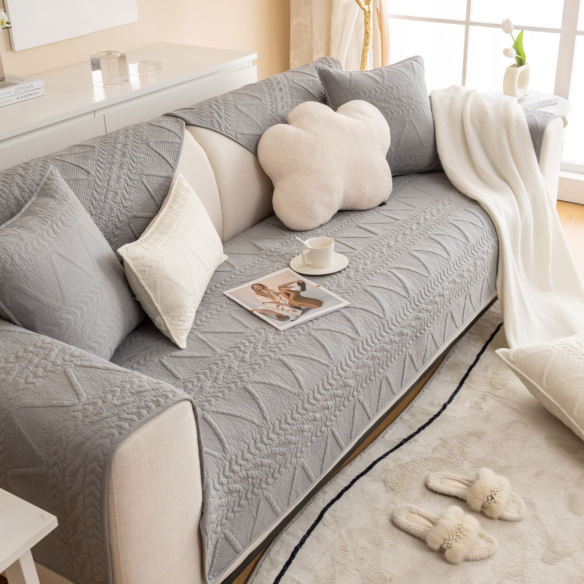 Geometric Textured Cotton Quilted Sofa Cover, Non-Slip Washable Couch Protector on a modern couch with pillows and cup of coffee.