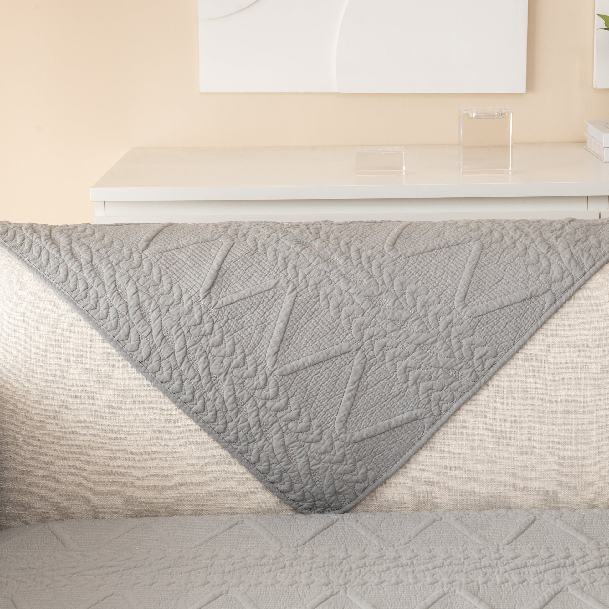Geometric Textured Cotton Quilted Sofa Cover, Non-Slip Washable Couch Protector in gray with sculptural modern design.