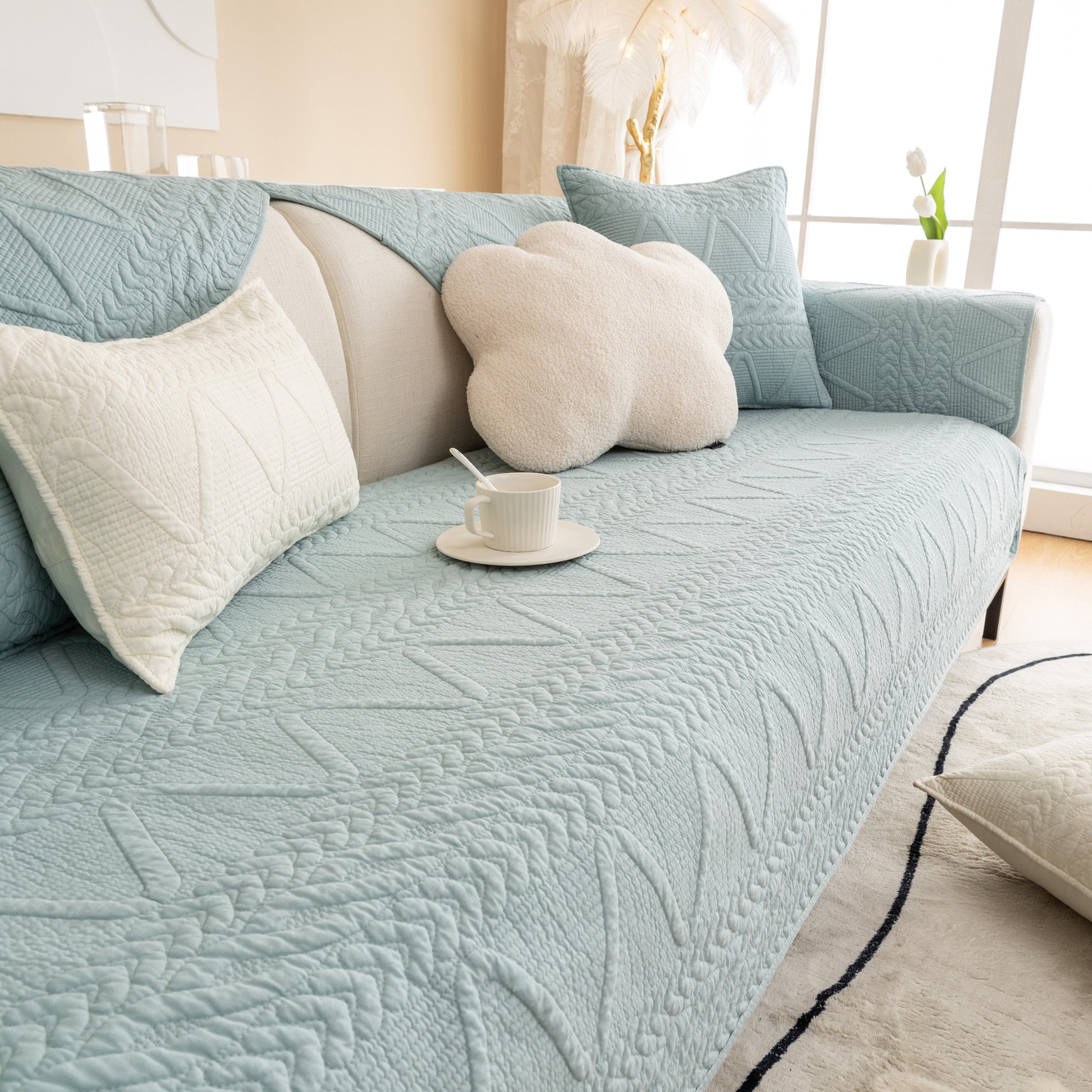 Light blue Geometric Textured Cotton Quilted Sofa Cover, Non-Slip Washable Couch Protector on a modern sofa with plush cushions.