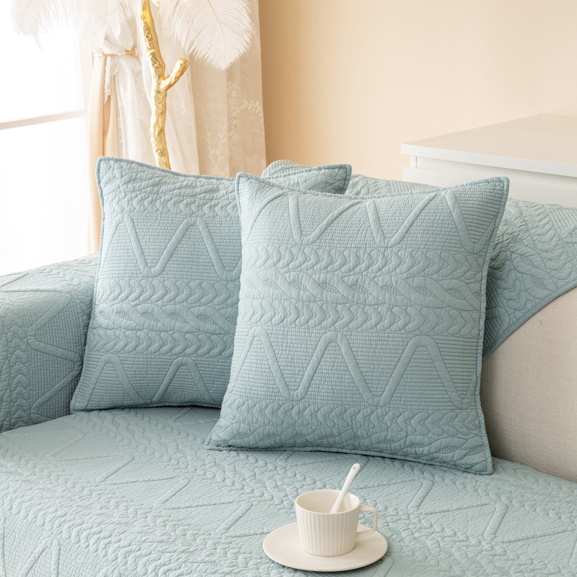 Geometric Textured Cotton Quilted Sofa Cover, Non-Slip Washable Couch Protector in modern living room setting with tea cup.