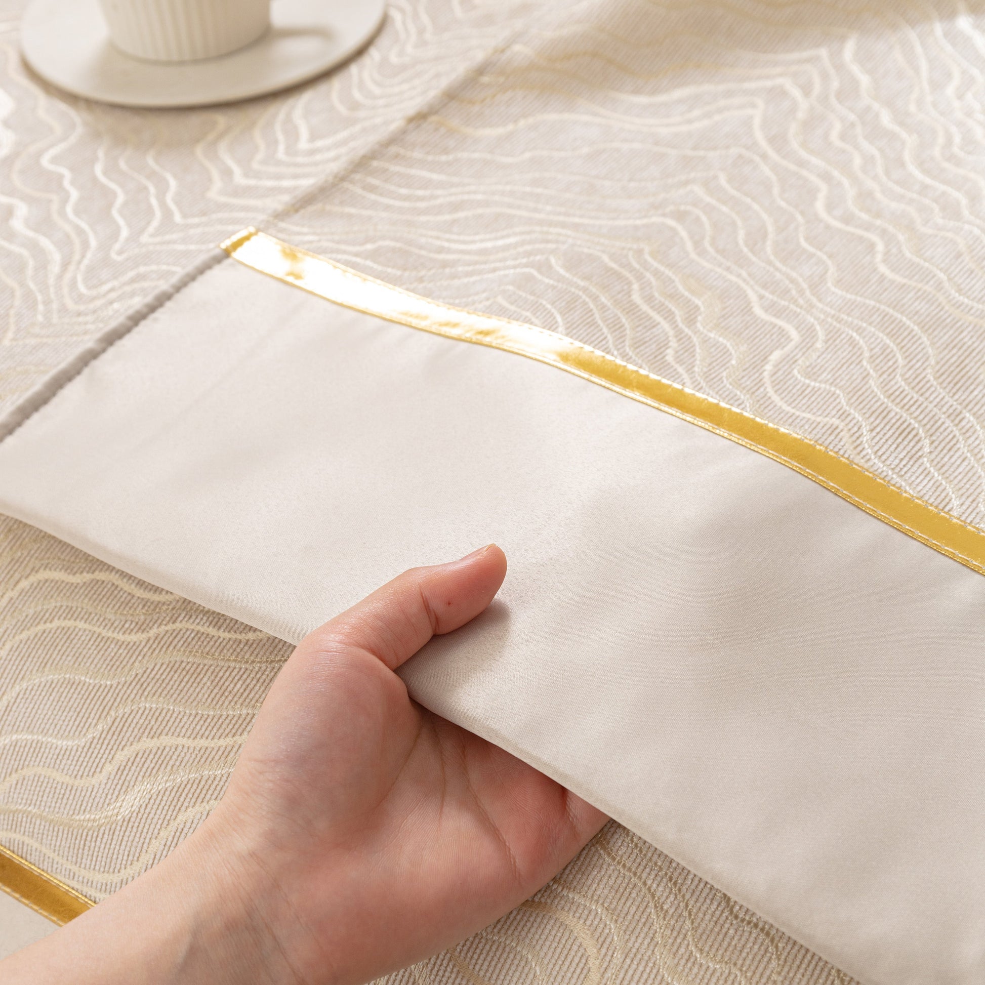 Close-up of hand touching Modular Sofa Cover for Sectionals, Gold Striped Non-Slip Couch Protector with wave pattern and gold stripes.