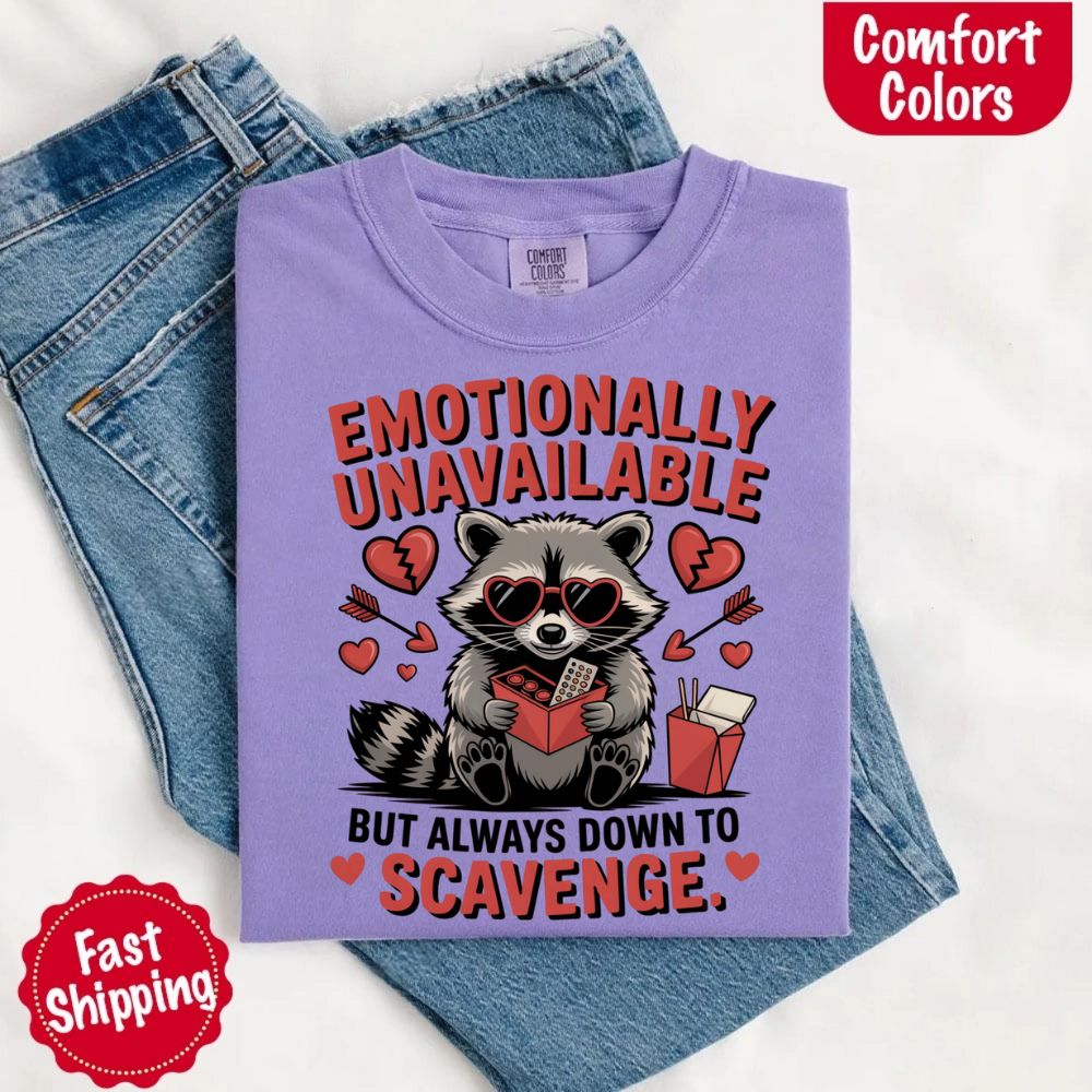 Comfort Colors Emotionally Unavailable Raccoon T-Shirts with moody raccoon print on purple backdrop, showcasing fun and quirky vibe.