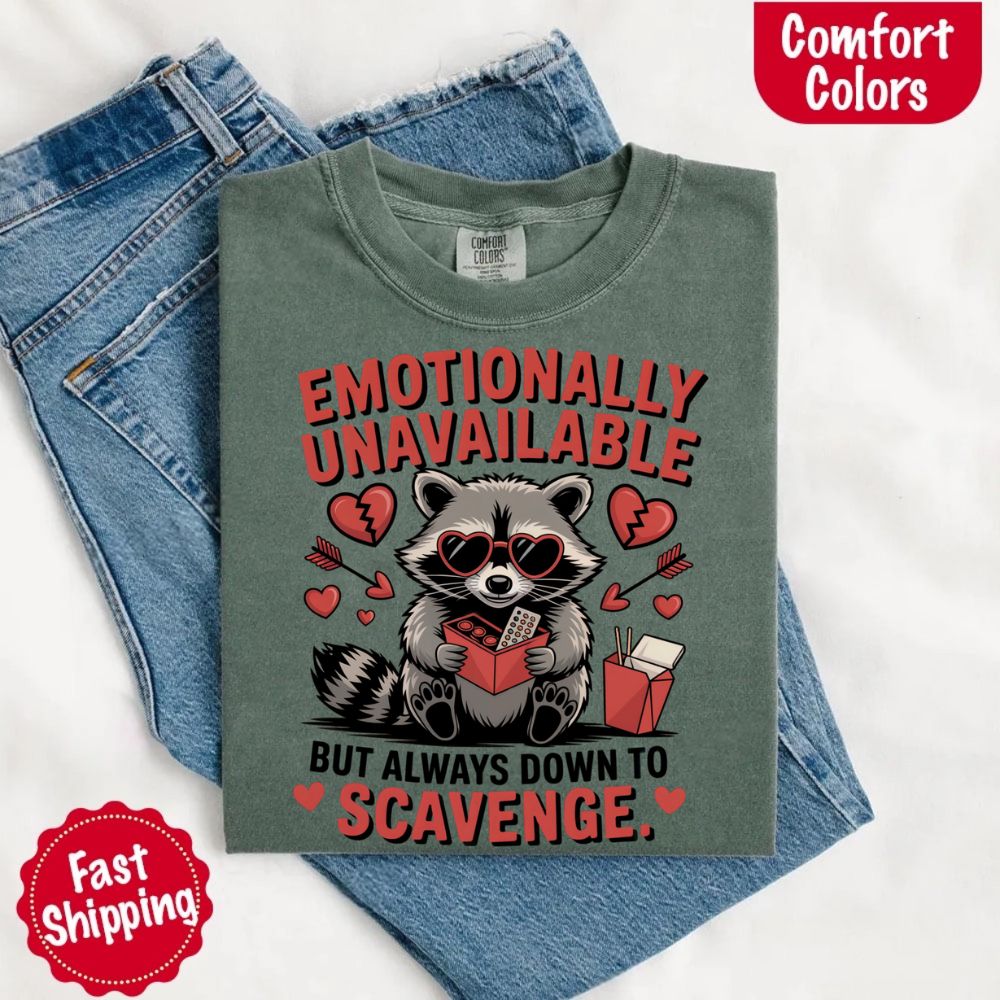 Comfort Colors Emotionally Unavailable Raccoon T-Shirts with moody raccoon and heart graphics on denim backdrop, fast shipping