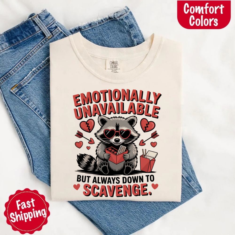 Comfort Colors Emotionally Unavailable Raccoon T-Shirts on jeans, featuring moody raccoon design, heart graphics, and fast shipping badge.