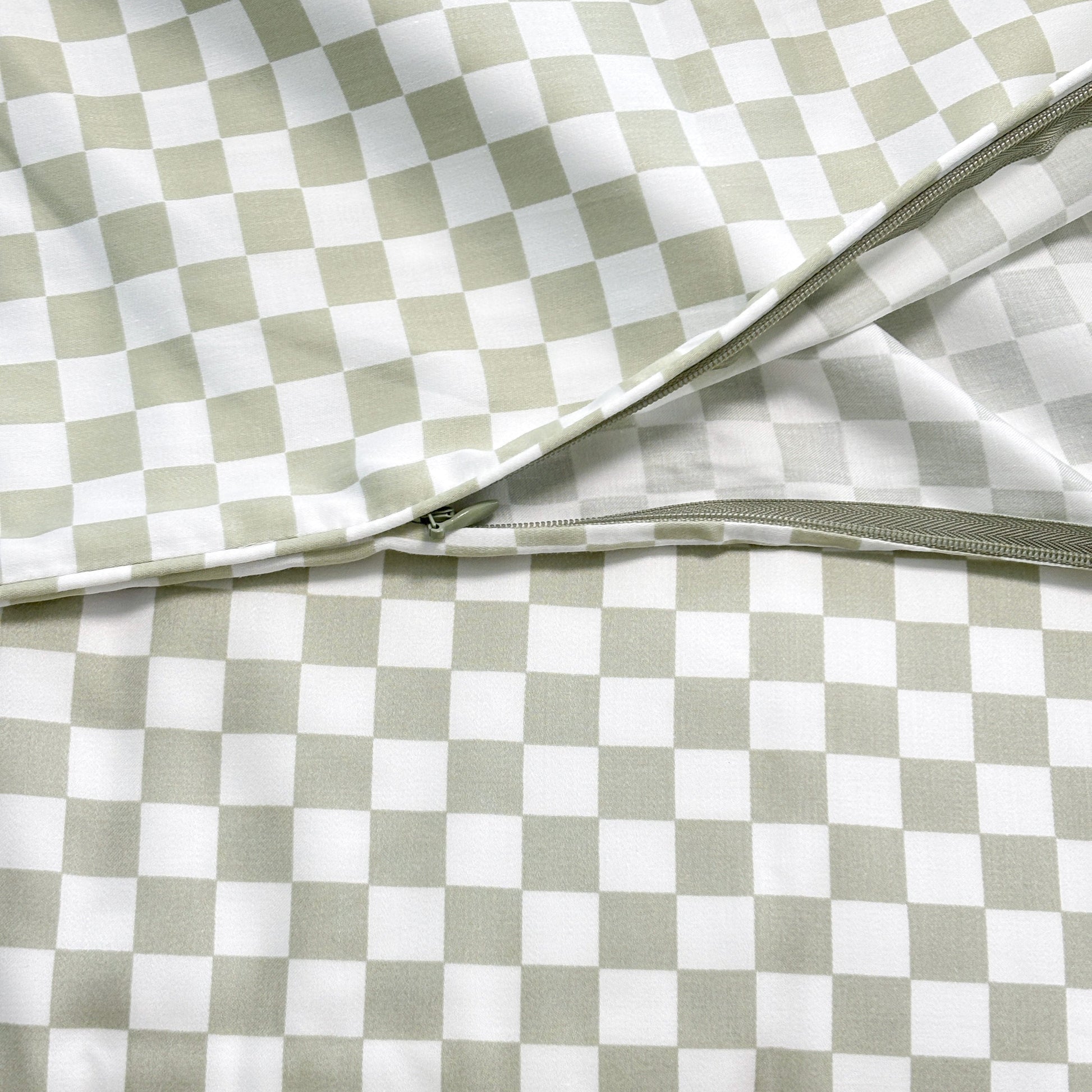 Close-up of SHNUGGLE Bedding Set Sage Checker showing zipper detail on checkered fabric.
