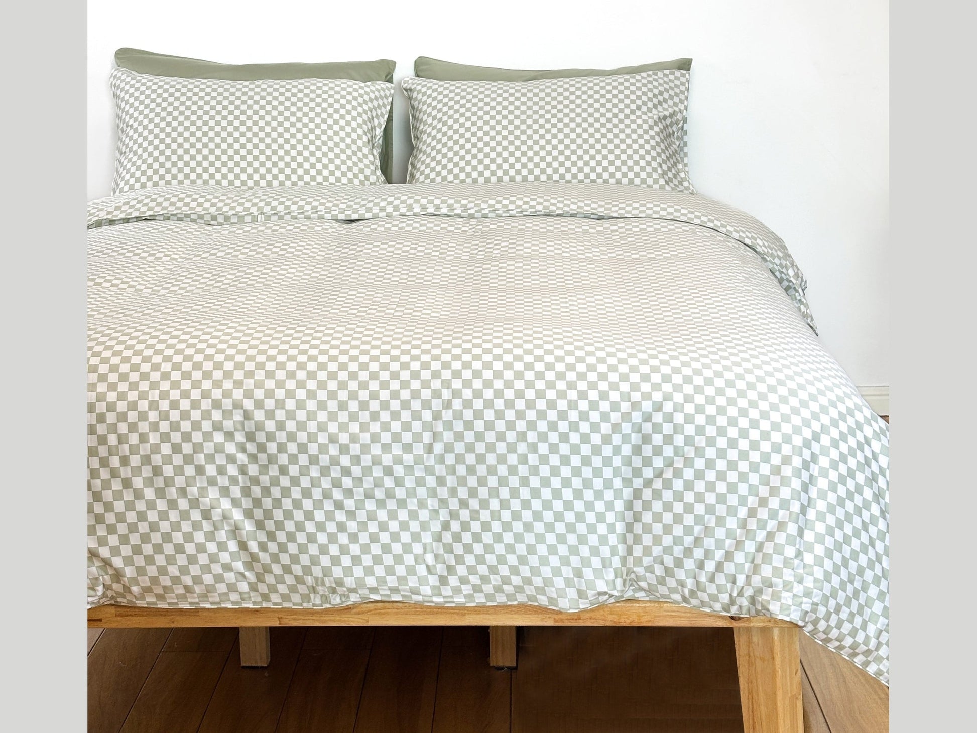 Checkered grey and white bedding set on bed with wooden frame and checked pillows