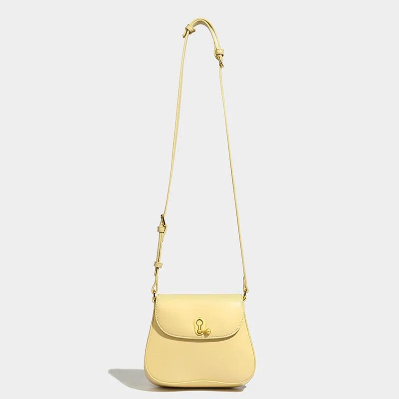Light yellow leather crossbody shoulder bag with adjustable strap on neutral background.