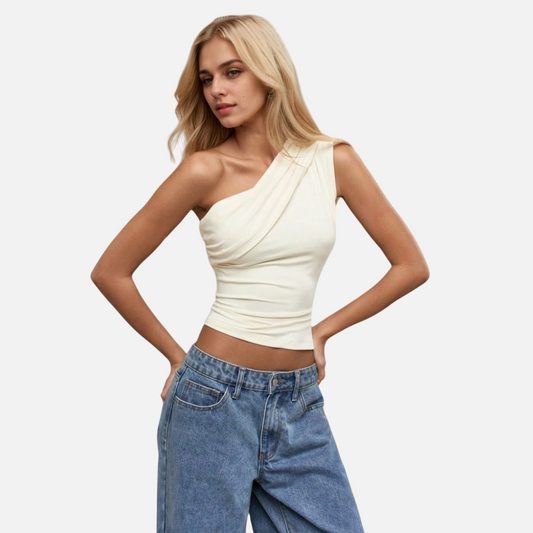 Woman wearing Sierra Slant Off-Shoulder Top in apricot, showcasing slanted neckline and slim-fit design with jeans.