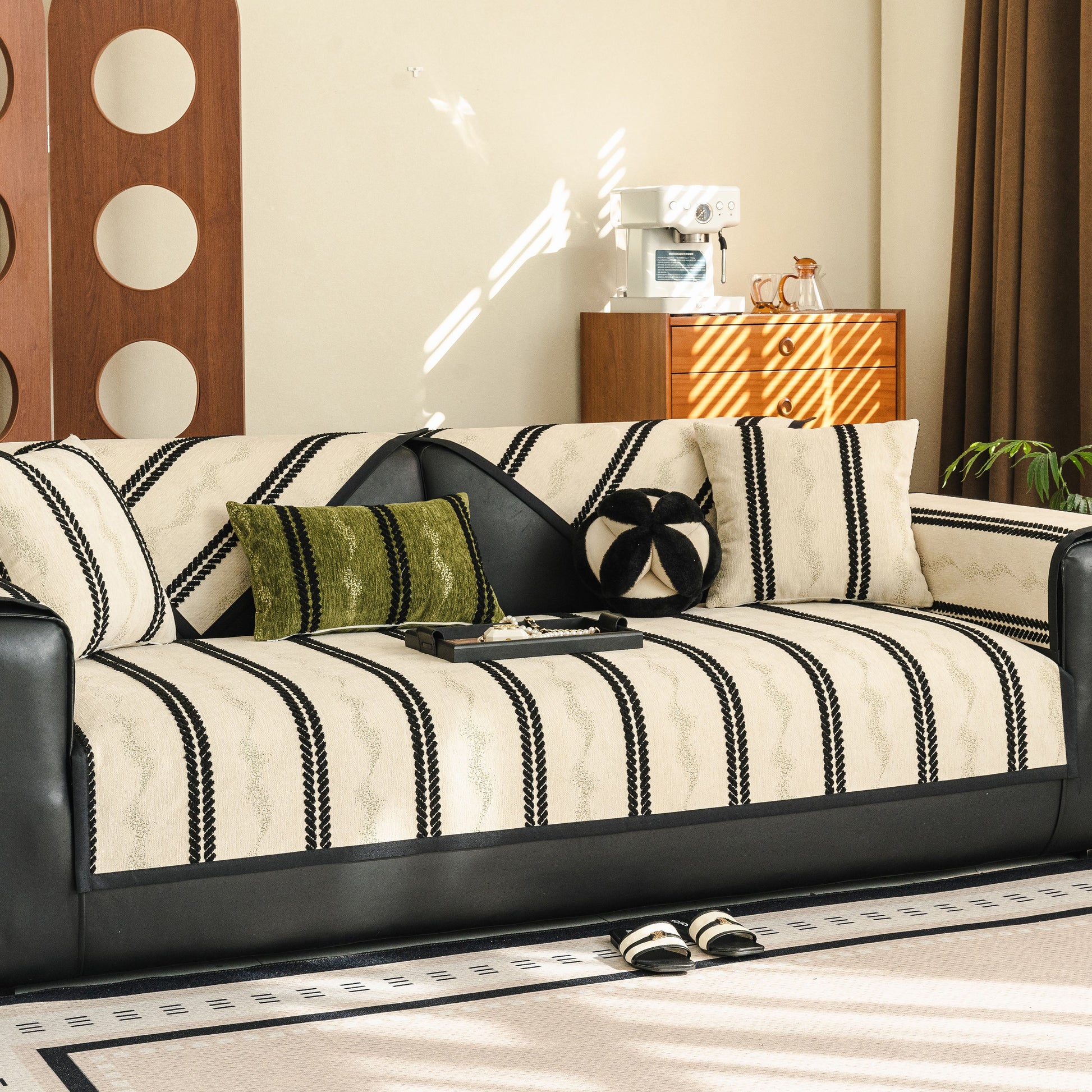 Non-Slip Sofa Cover with Thick Chenille Texture Woven Stripe Couch Protector Throw on a black leather couch in a living room