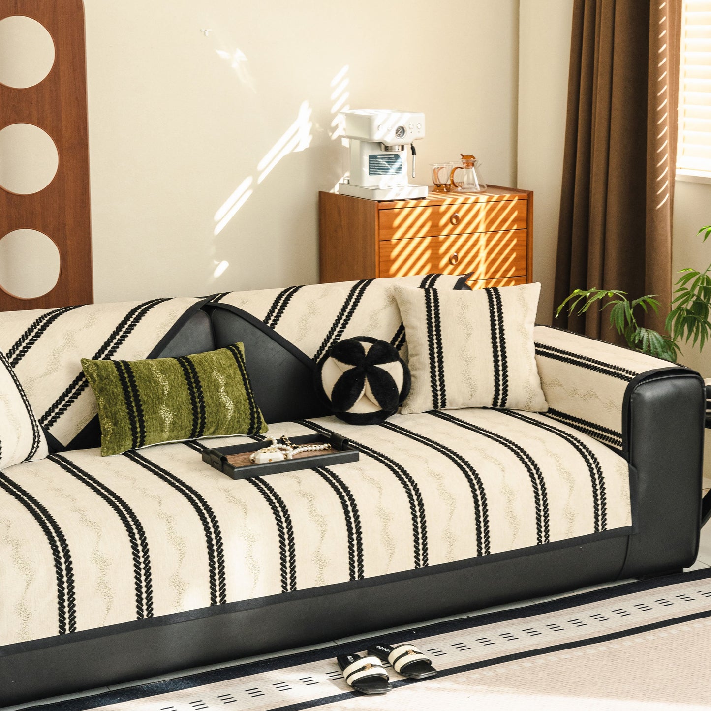 Non-Slip Sofa Cover with Thick Chenille Texture Woven Stripe Couch Protector Throw on a black leather couch in a living room.