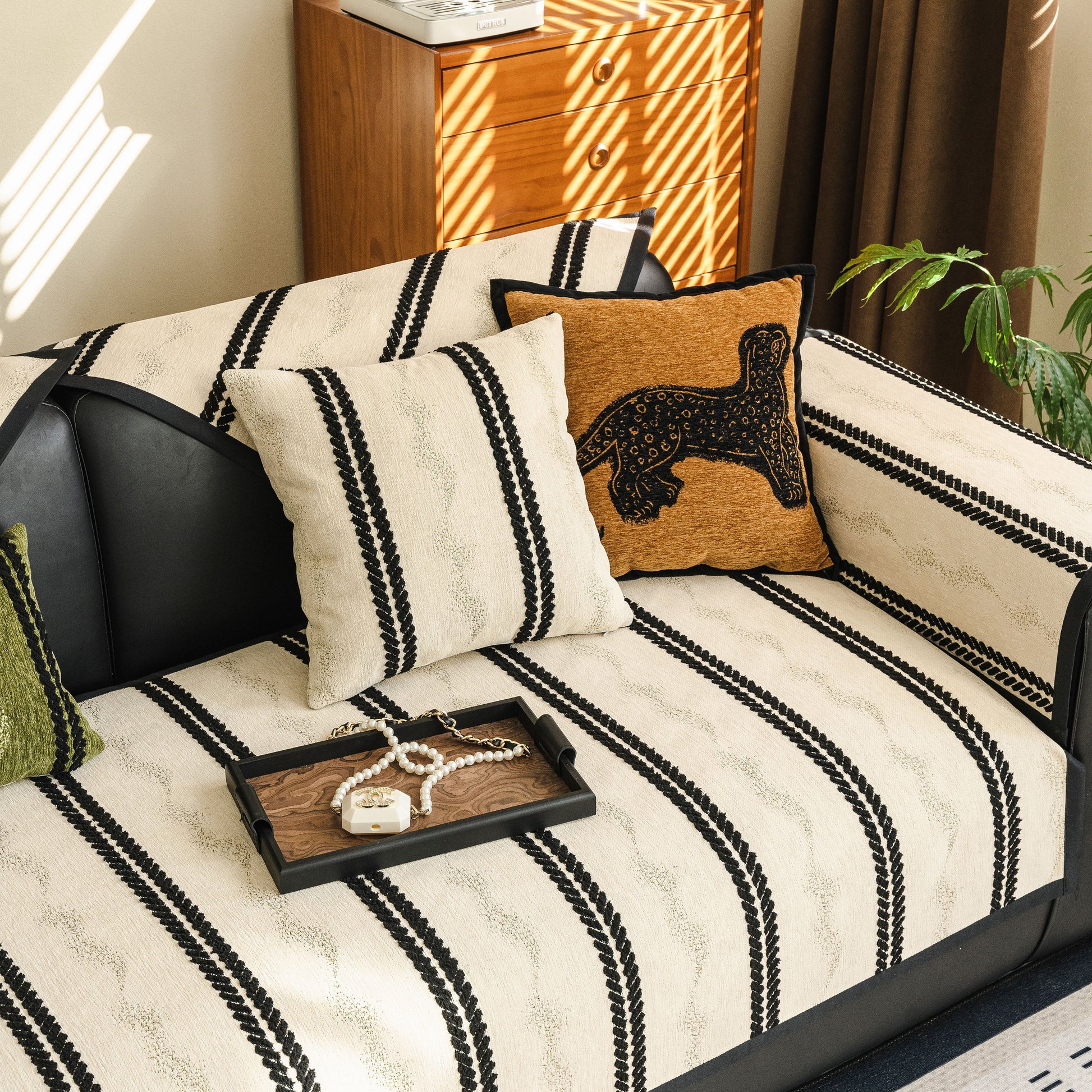 Non-Slip Sofa Cover with Thick Chenille Texture Woven Stripe Couch Protector Throw displayed on a black leather sofa.