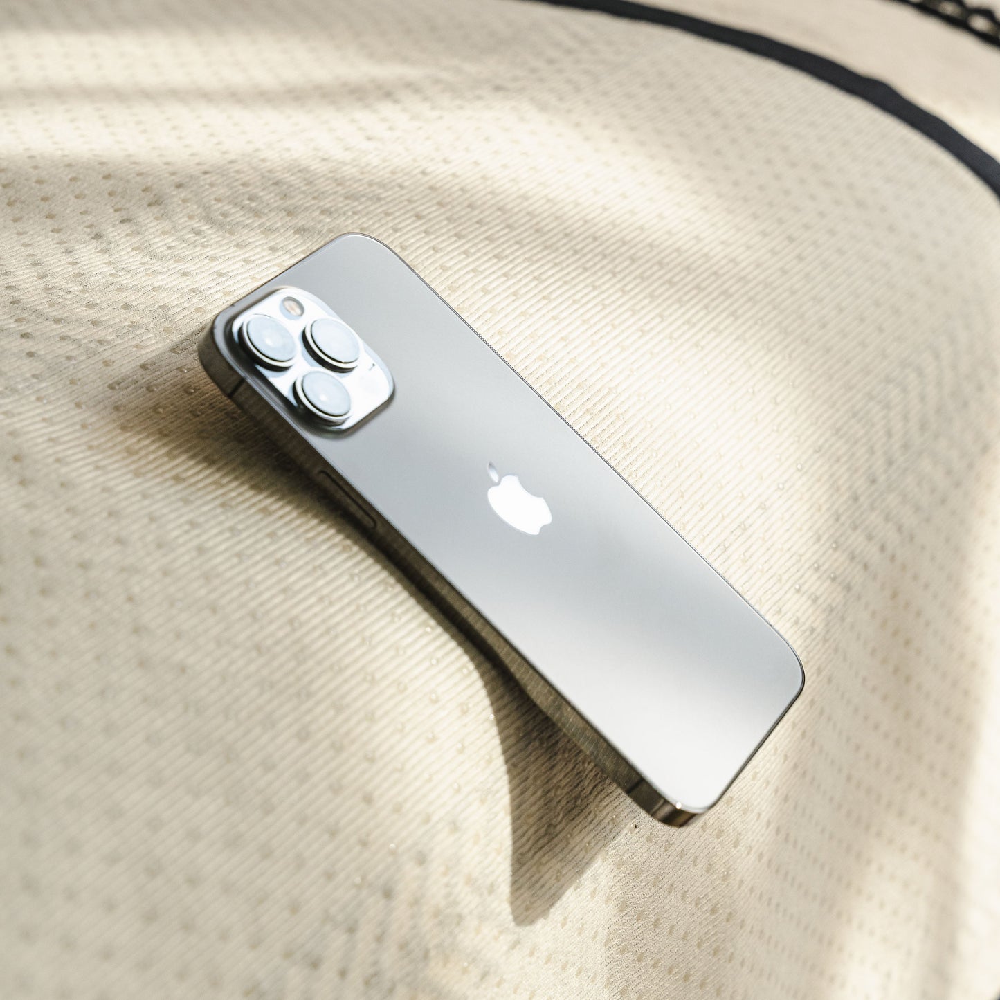 Silver smartphone with camera lenses on beige patterned fabric