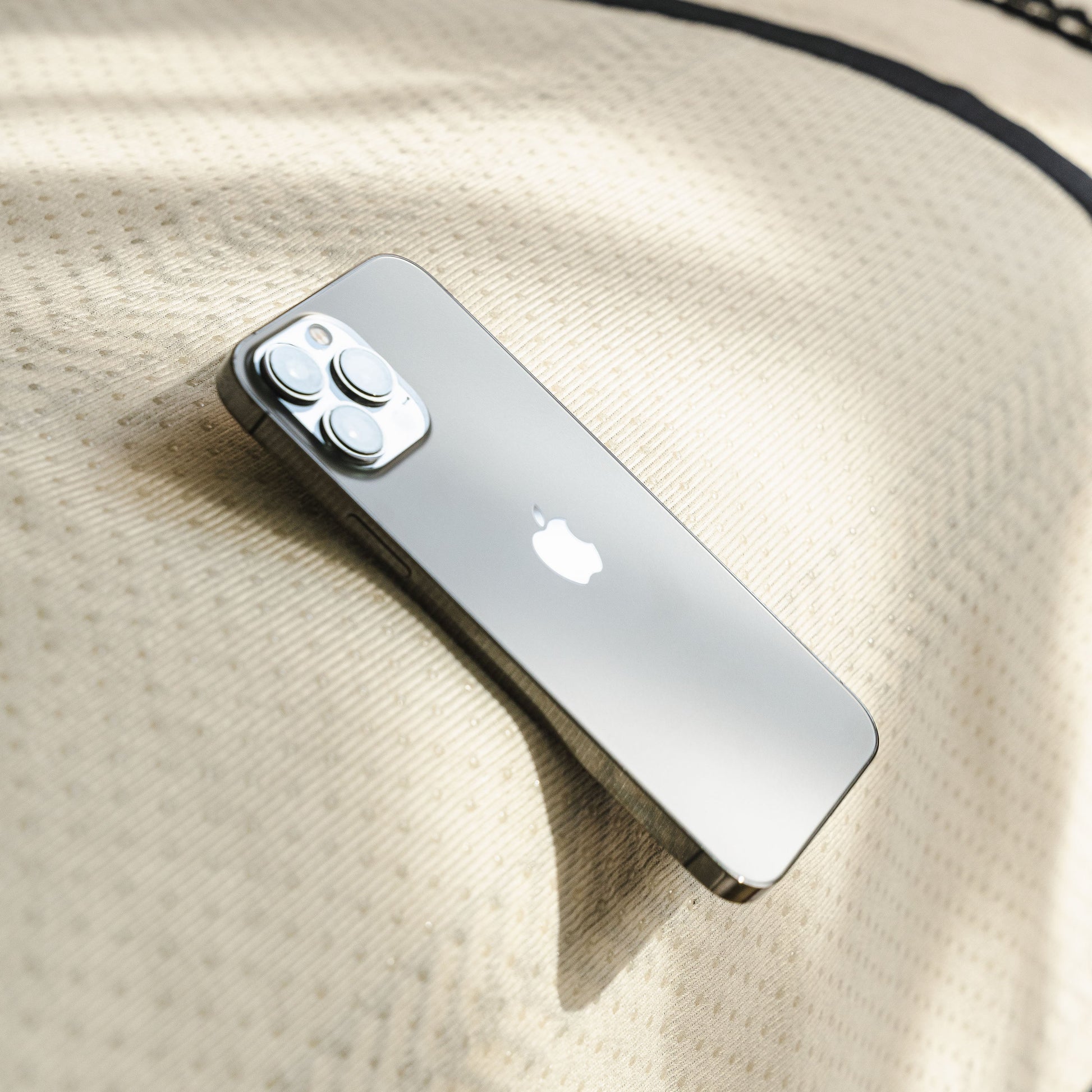 Silver smartphone with camera lenses on beige patterned fabric