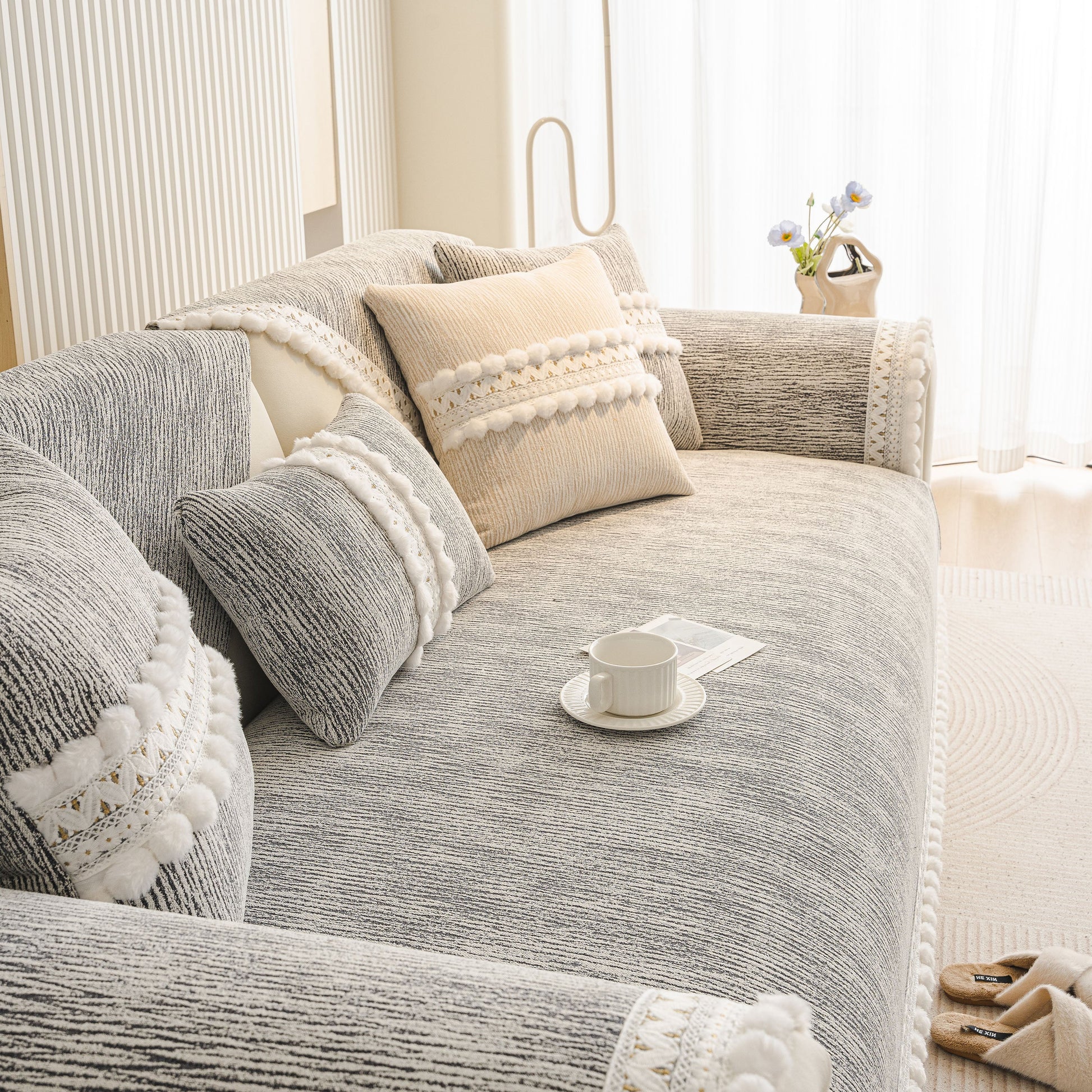 Soft Chenille Sectional Sofa Cover with Pom Pom Trim – Non-Slip Couch Protector in gray with decorative pillows and trim.