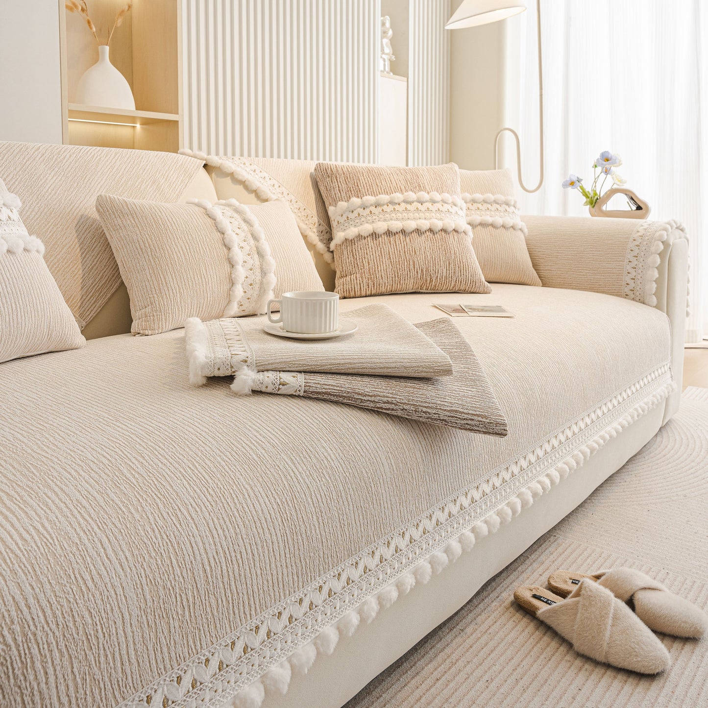 Soft Chenille Sectional Sofa Cover with Pom Pom Trim – Non-Slip Couch Protector in beige with lace trim and pom pom fringe.