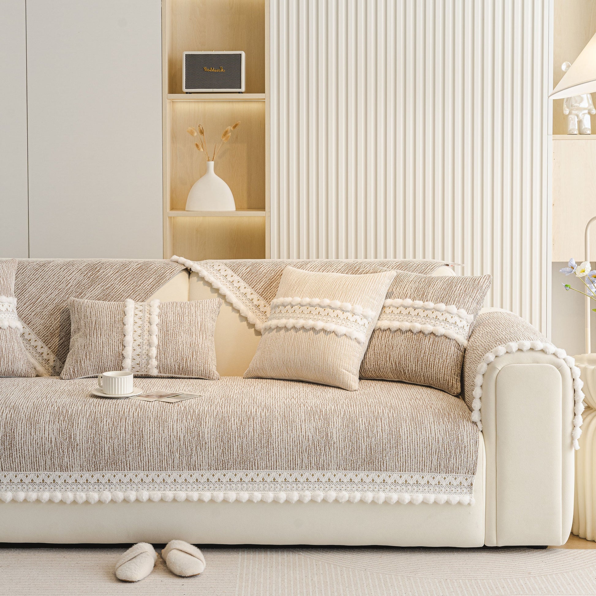 Soft Chenille Sectional Sofa Cover with Pom Pom Trim – Non-Slip Couch Protector in beige with decorative pillows and pom-pom fringe.
