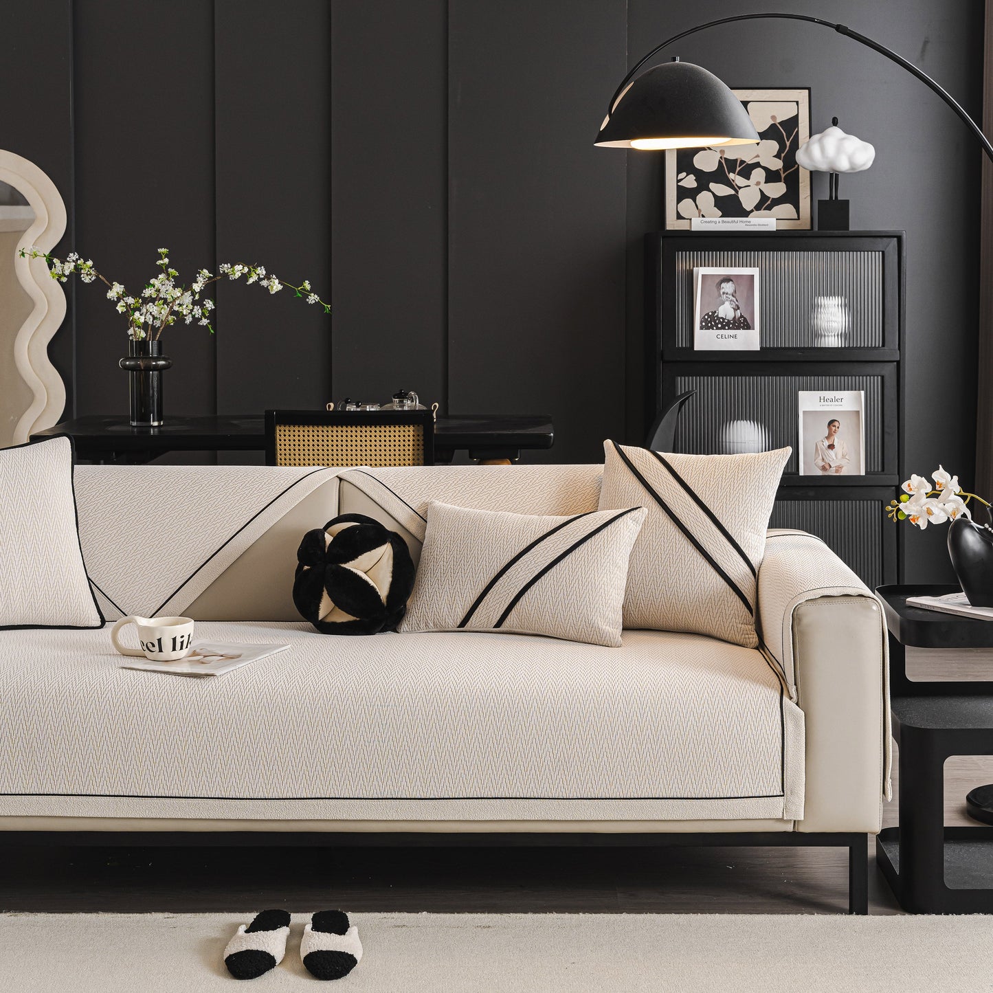 Modern living room with beige sofa featuring decorative cushions and stylish black accents, surrounded by contemporary decor elements.