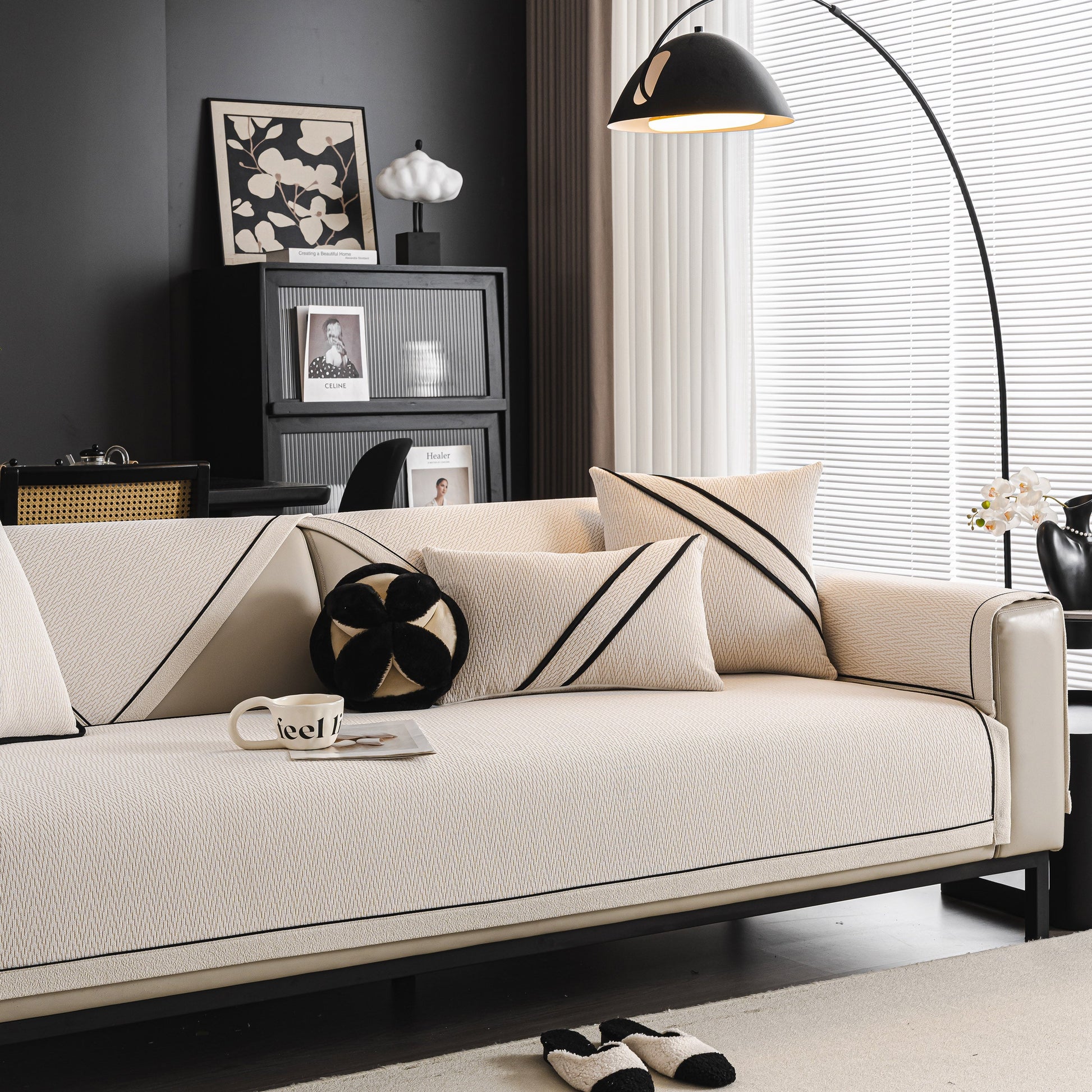 Modern living room with a beige couch featuring black striped pillows and under a stylish black arc lamp.