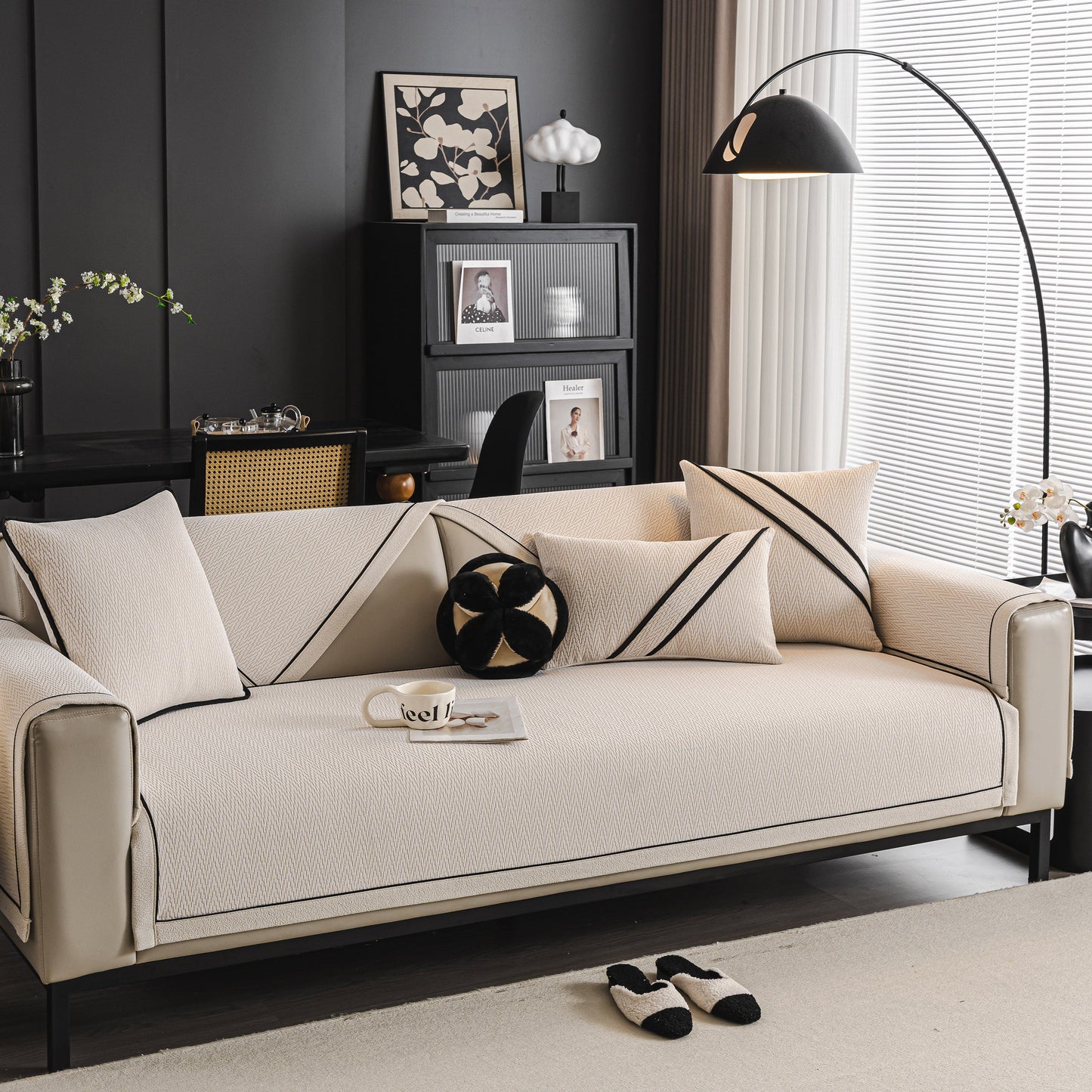 Modern living room with beige couch featuring stylish cushions and black accents, illuminated by an arc floor lamp near a window.
