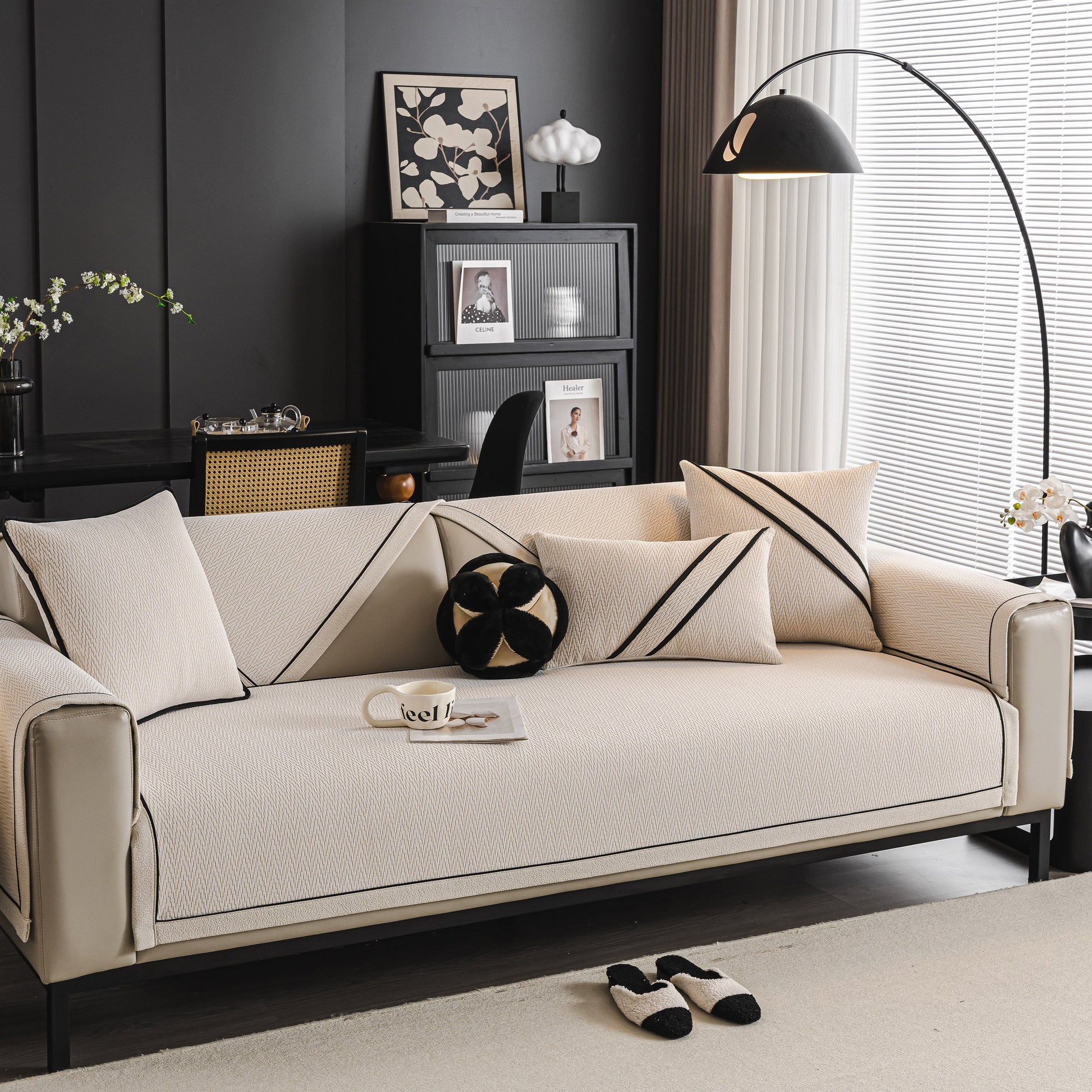 Modern living room with beige couch featuring stylish cushions and black accents, illuminated by an arc floor lamp near a window.