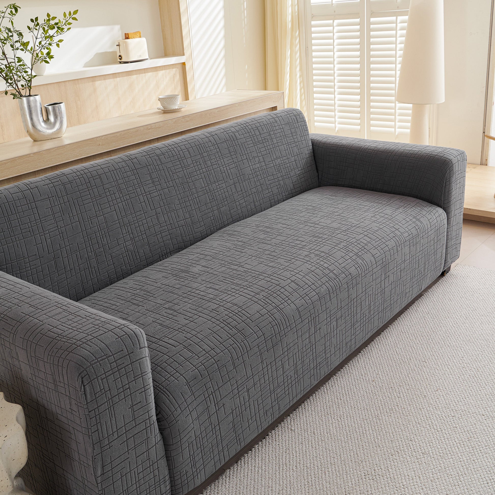 Embossed Lines Couch Covers Stretchable Non-Slip & Washable Sofa Slipcovers on a grey couch in a modern living room.