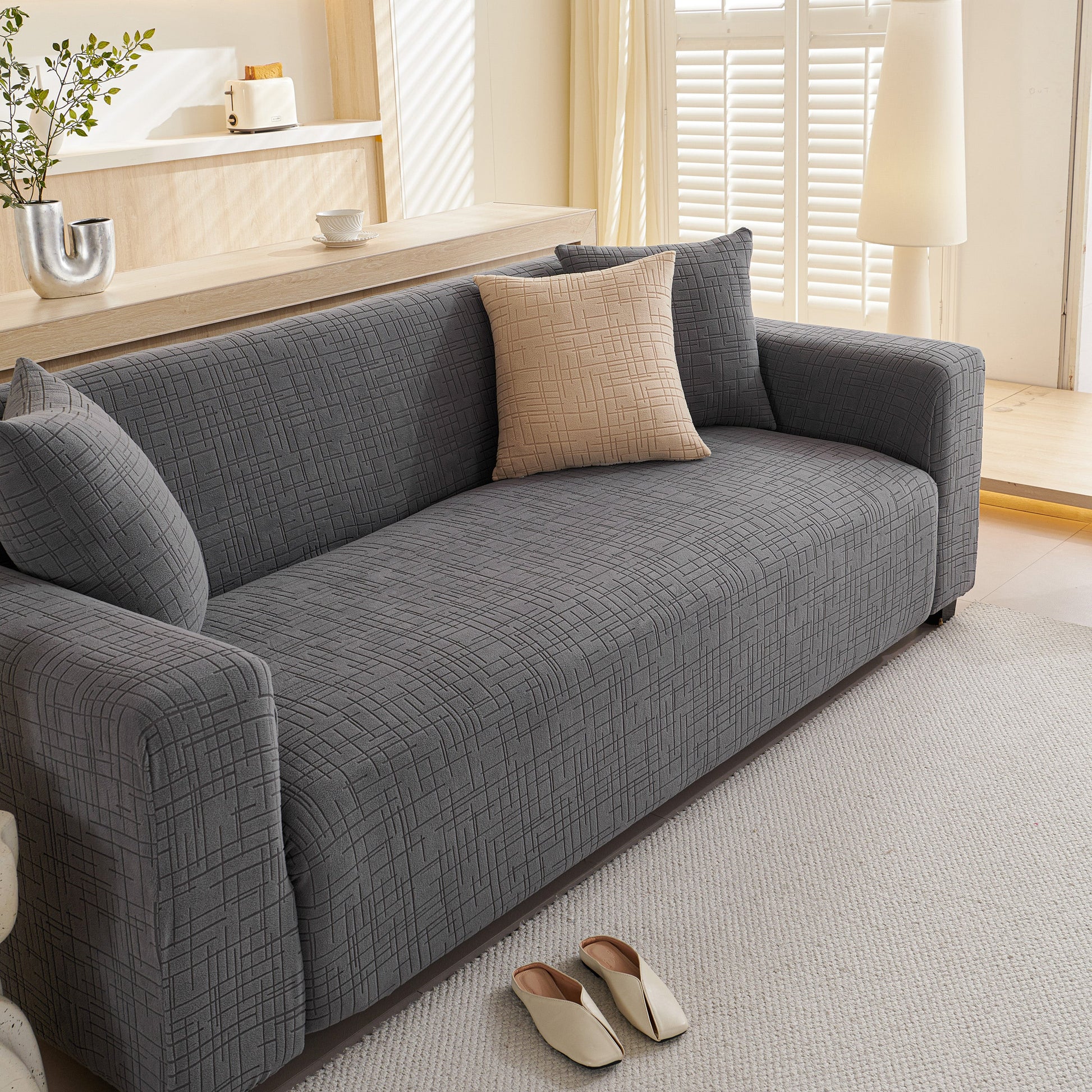 Embossed Lines Couch Covers Stretchable Non-Slip & Washable Sofa Slipcovers on a gray couch in a living room setting.