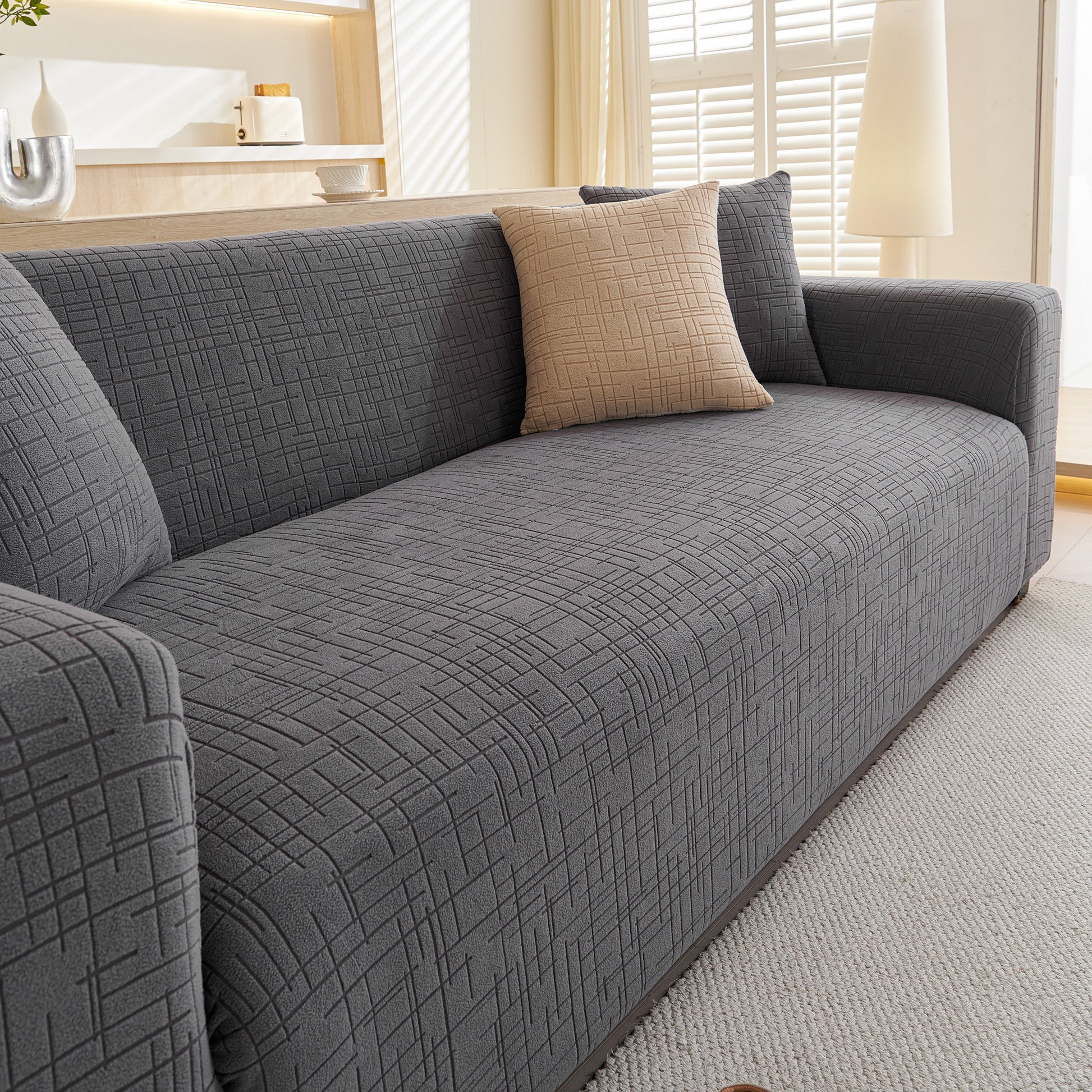 Embossed Lines Couch Covers Stretchable Non-Slip & Washable Sofa Slipcovers on a modern grey sofa in a bright living room.