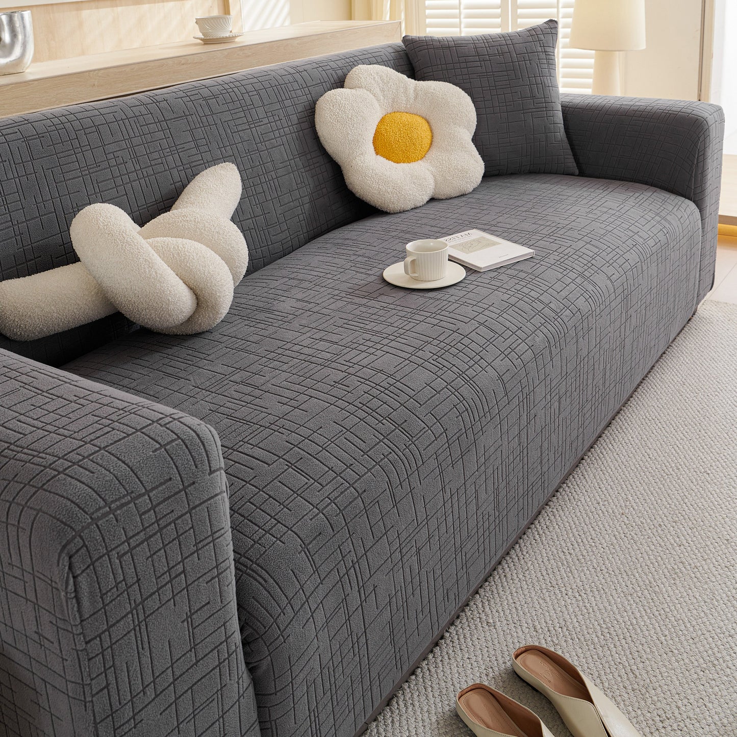 Embossed Lines Couch Covers Stretchable Non-Slip & Washable Sofa Slipcovers on a grey sofa with decorative pillows and a cup.