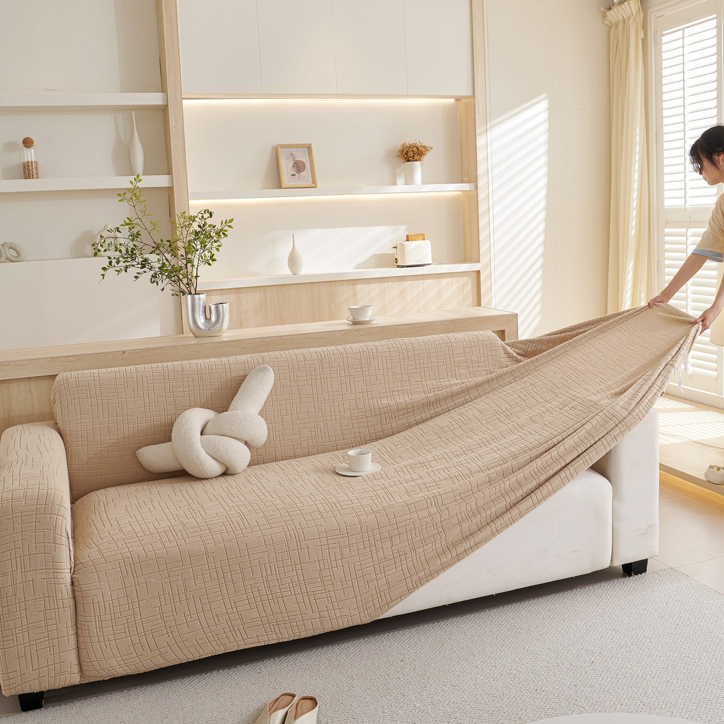 Person adjusting Embossed Lines Couch Covers Stretchable Non-Slip & Washable Sofa Slipcovers in a modern living room.