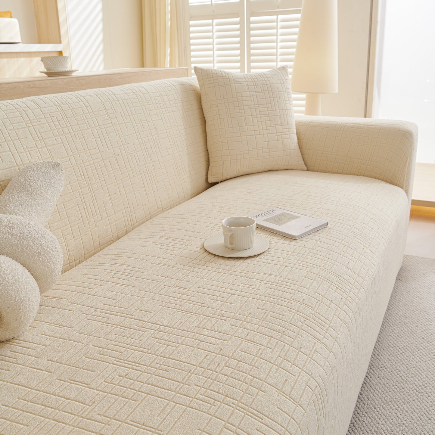 Embossed Lines Couch Covers Stretchable Non-Slip & Washable Sofa Slipcovers on a modern sofa with a book and coffee cup on the side