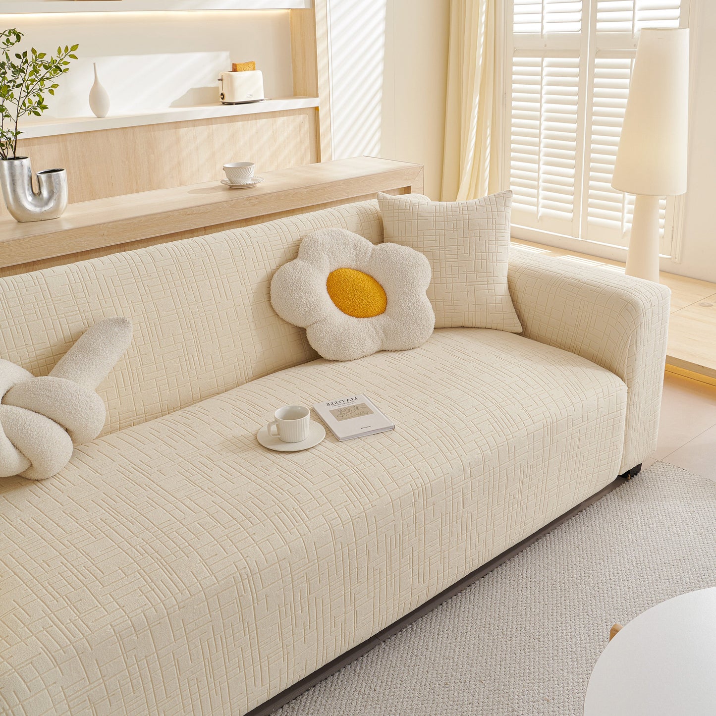 Embossed Lines Couch Covers Stretchable Non-Slip & Washable Sofa Slipcovers on a beige sofa with flower cushions in a bright room.