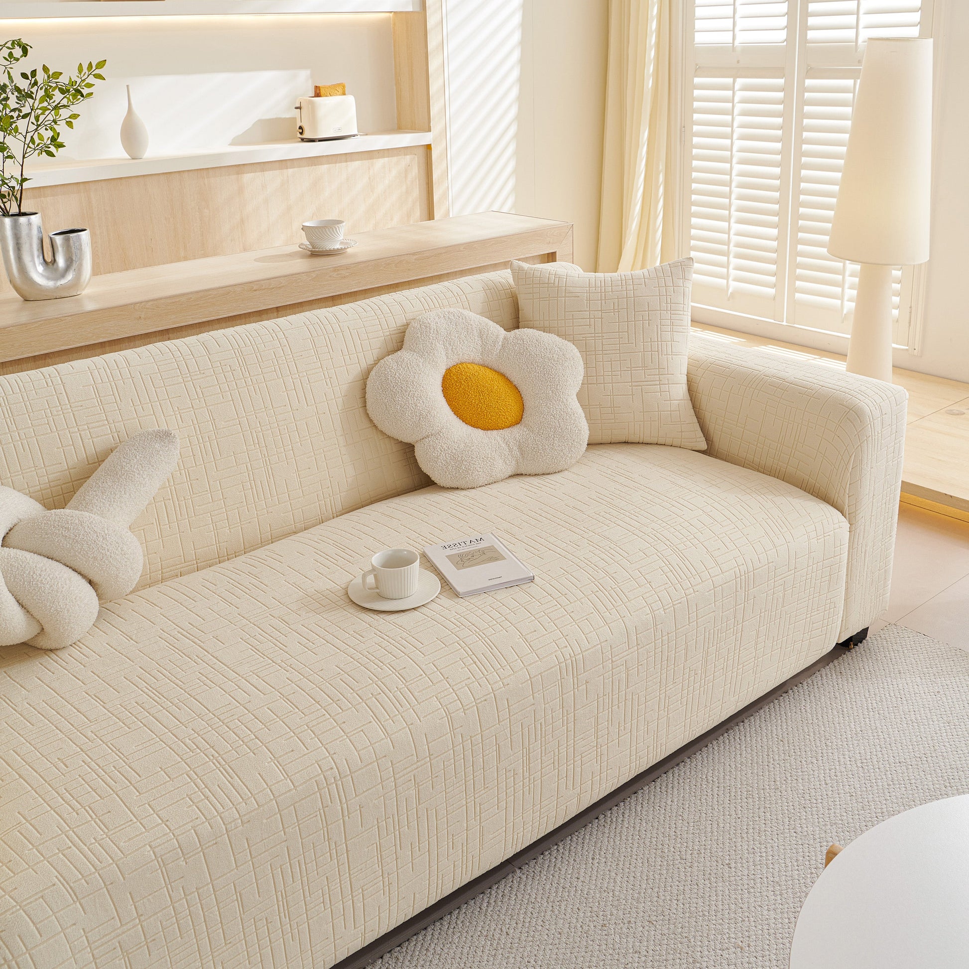 Embossed Lines Couch Covers Stretchable Non-Slip & Washable Sofa Slipcovers on a beige sofa with flower cushions in a bright room.