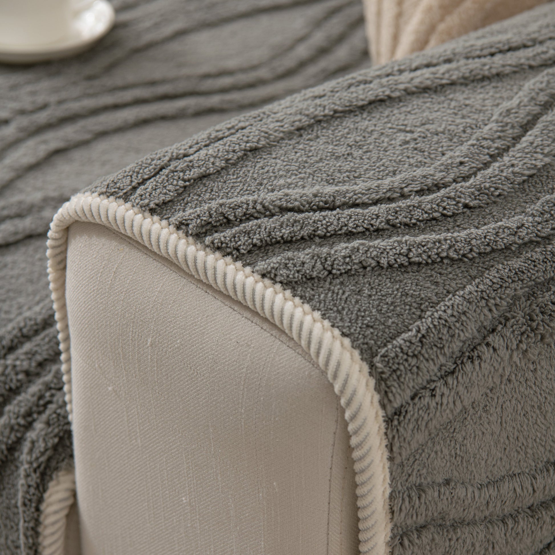 Winter Thickened Non-slip Blanket, Three-Dimensional Embossed Cotton Velvet Sofa Cover in grey on a beige sofa corner.