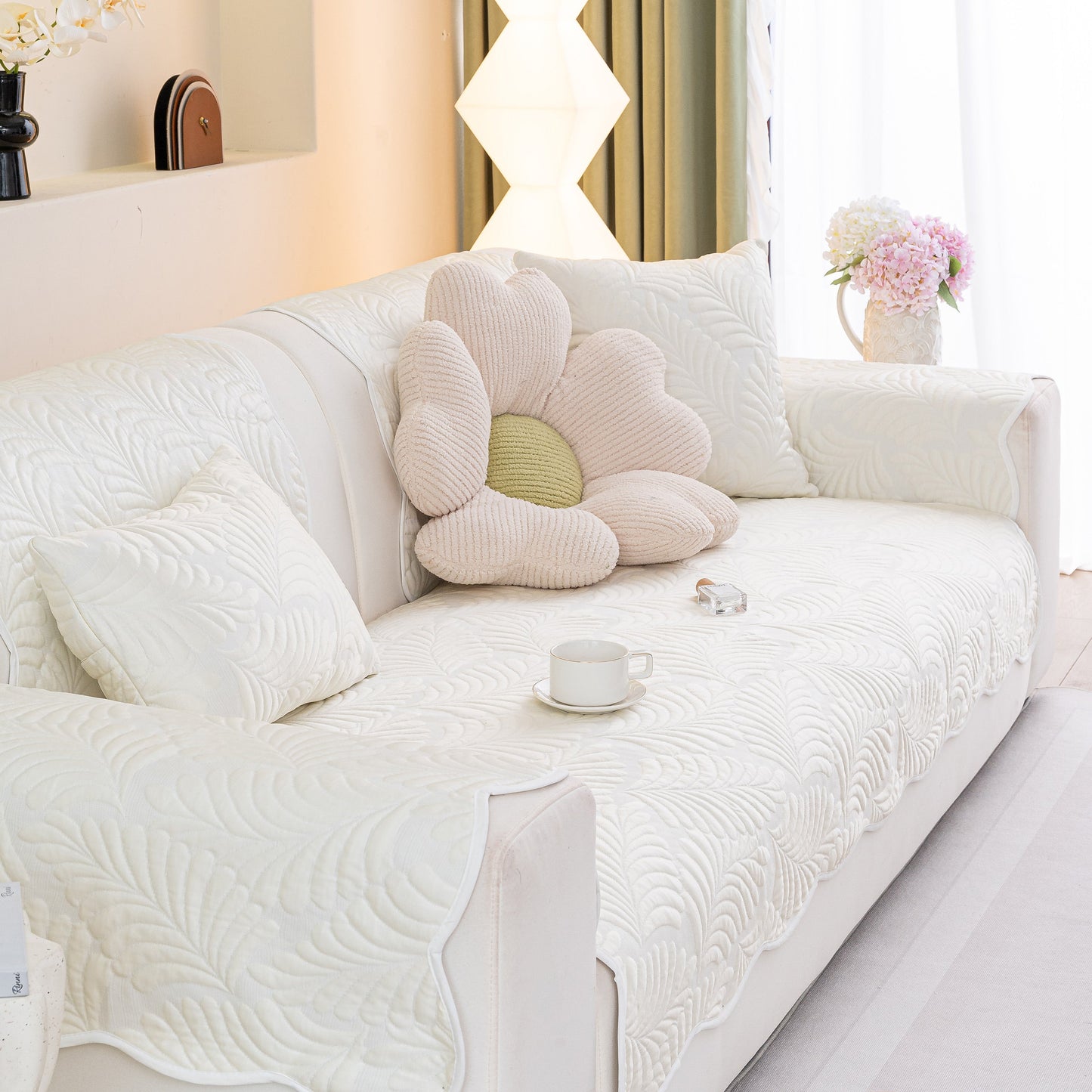Sofa Cover for Leather & Fabric Couches, 3D Leaf Embossed Quilted Furniture Covers on a white sofa with a floral pillow.