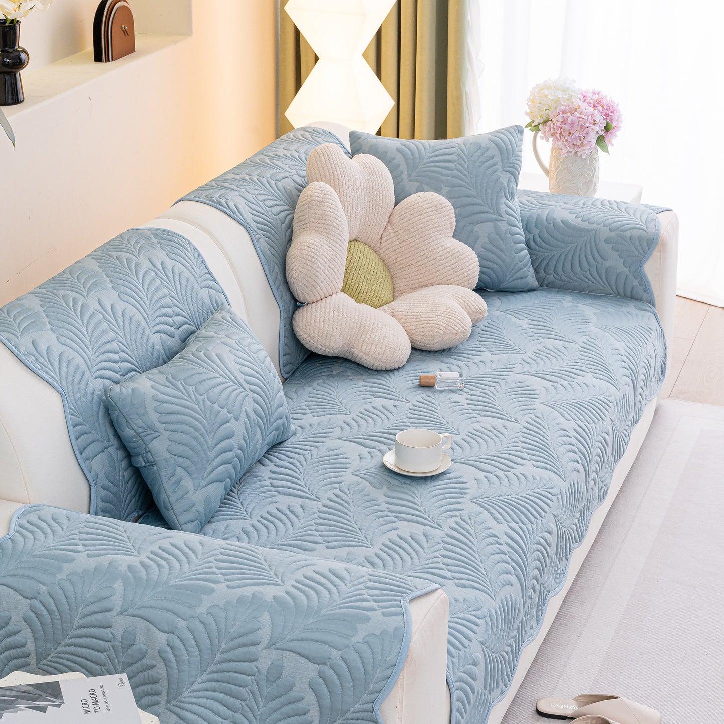 Sofa Cover for Leather & Fabric Couches, 3D Leaf Embossed Quilted Furniture Covers in blue with anti-slip backing on a white sofa.
