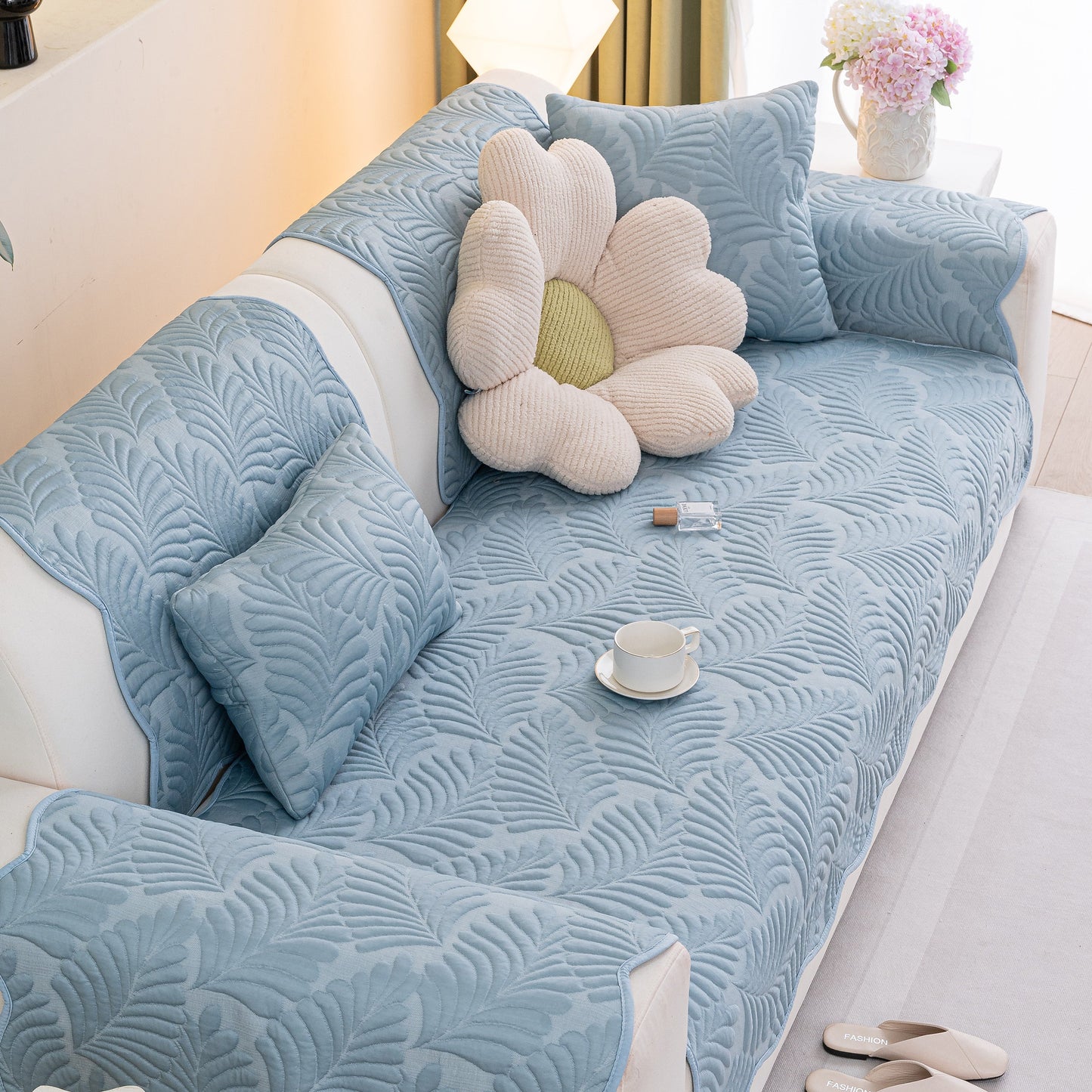 Sofa Cover for Leather & Fabric Couches, 3D Leaf Embossed Quilted Furniture Covers displayed on a sofa with flower pillow and tea cup