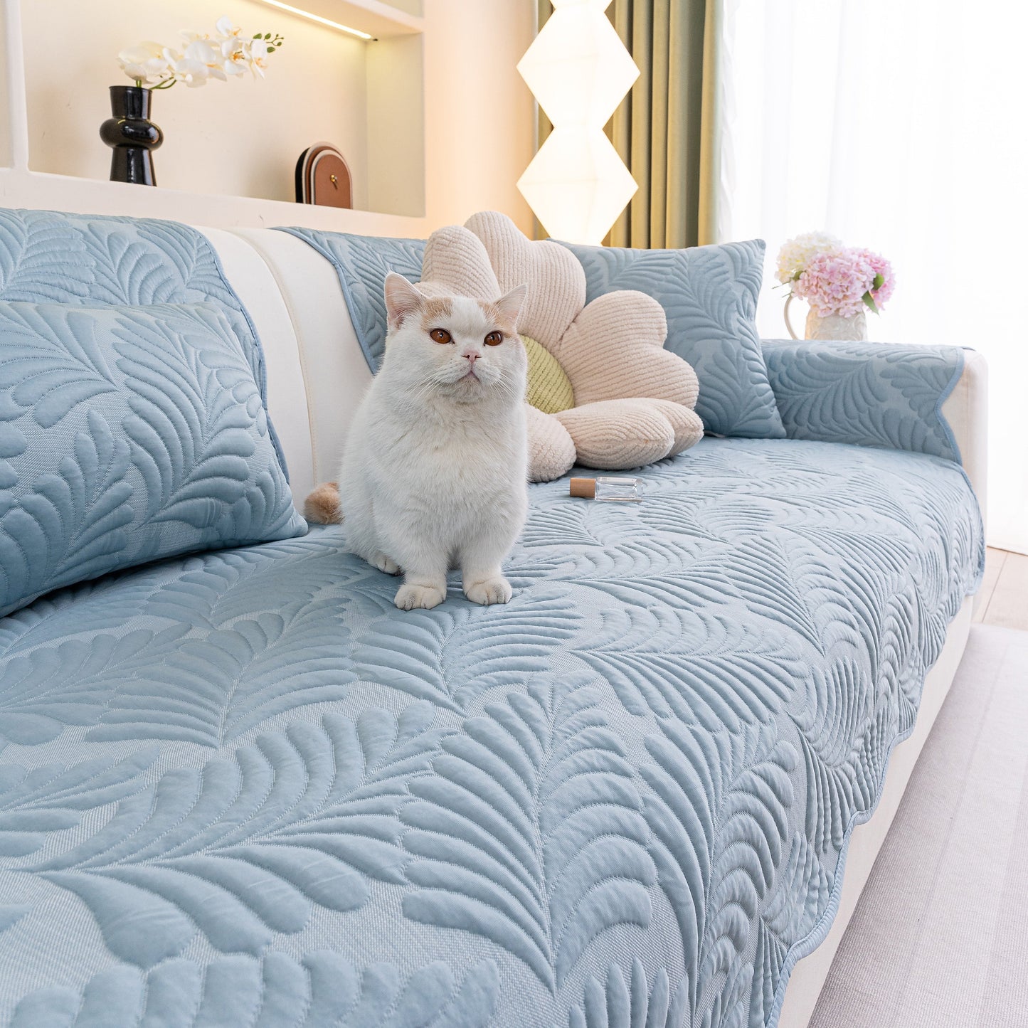 Sofa Cover for Leather & Fabric Couches, 3D Leaf Embossed Quilted Furniture Covers on a sofa with a cat sitting on top.