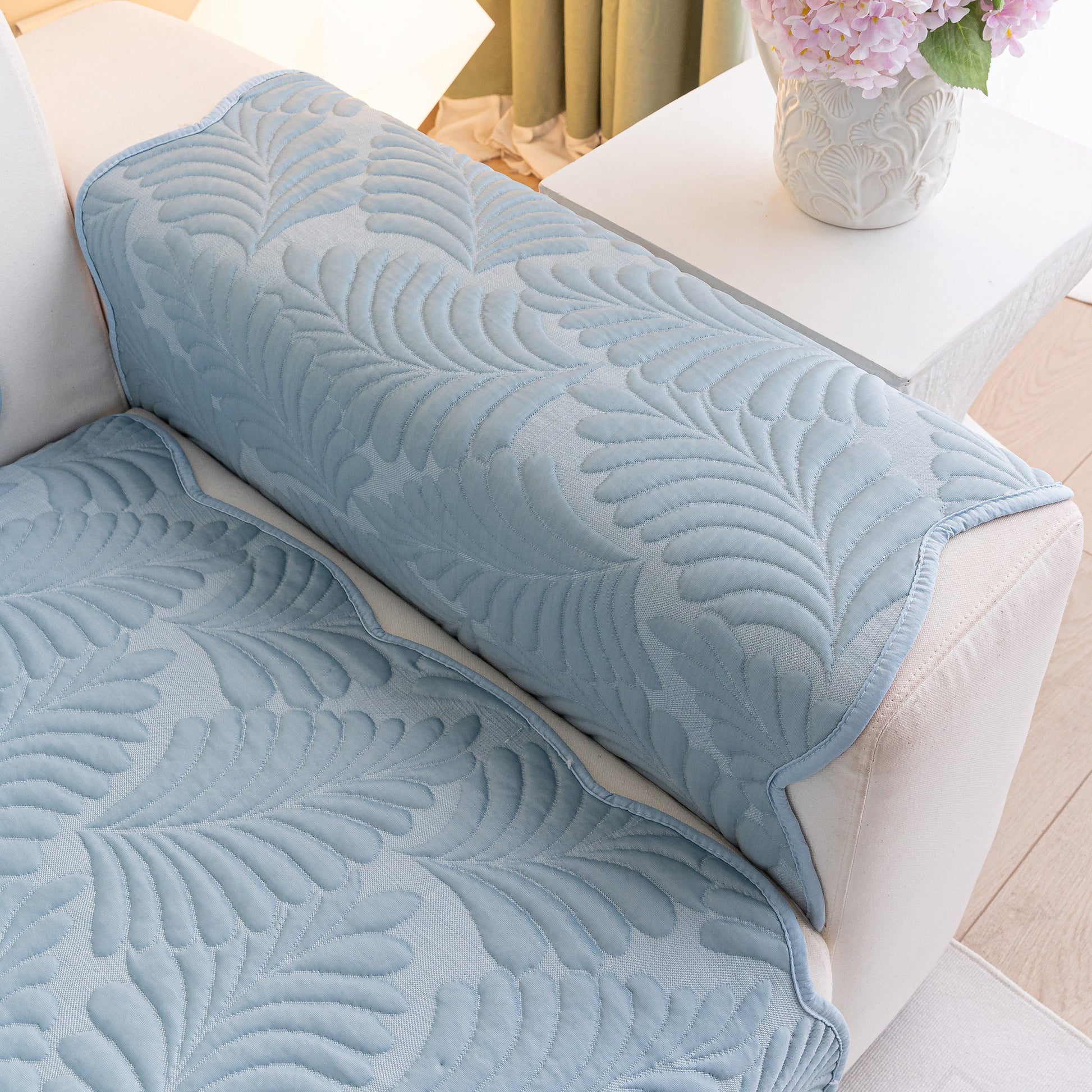 Sofa Cover for Leather & Fabric Couches, 3D Leaf Embossed Quilted Furniture Covers in blue with wave-cut edges on white sofa.